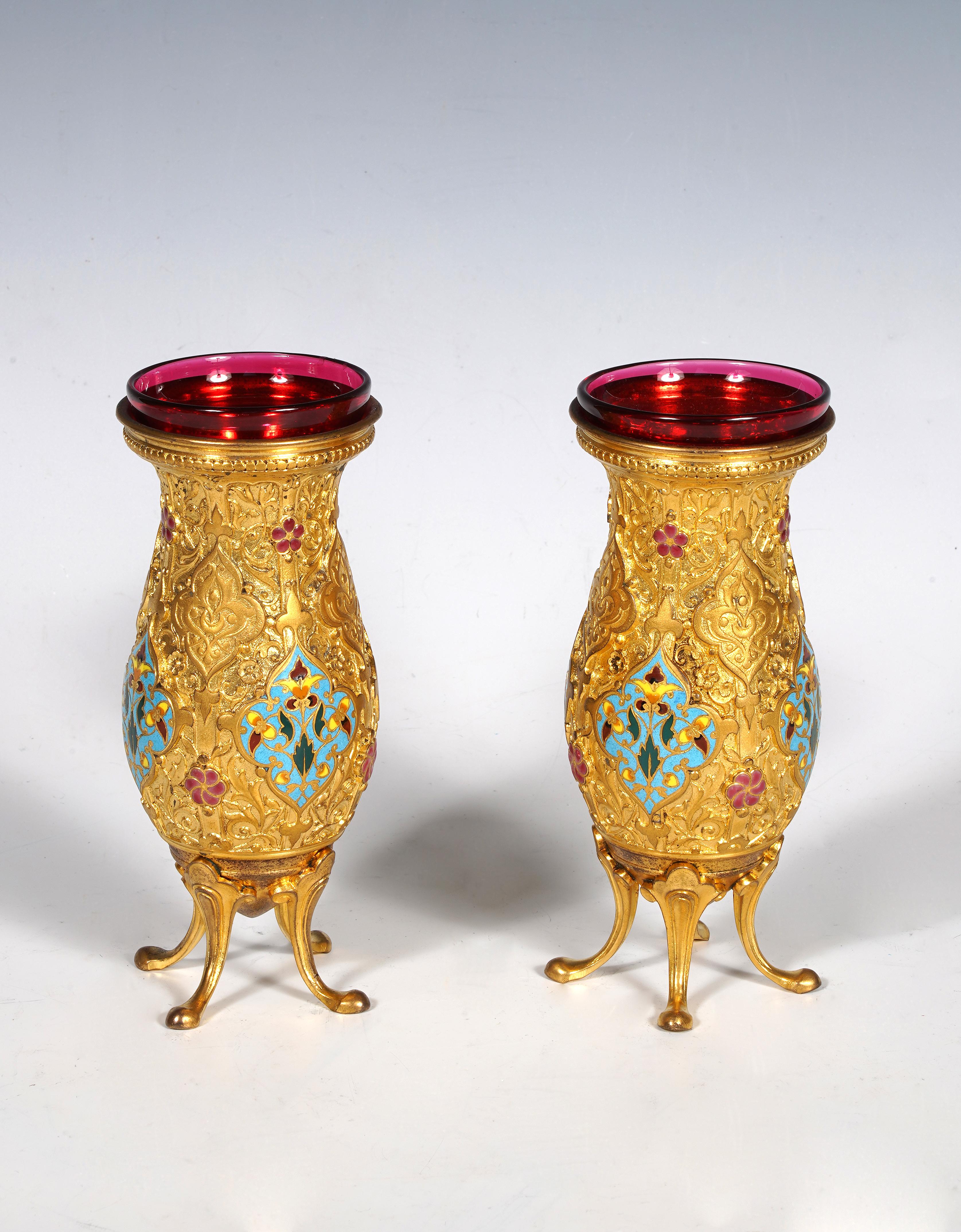 Firmato F. Barbedienne

Affascinante coppia di piccoli vasi in bronzo dorato parzialmente smaltato, con decorazione orientalista di arabeschi e fogliame. Sono ornati da cartigli con decorazioni bizantine in smalto cloisonné policromo. Foderate con