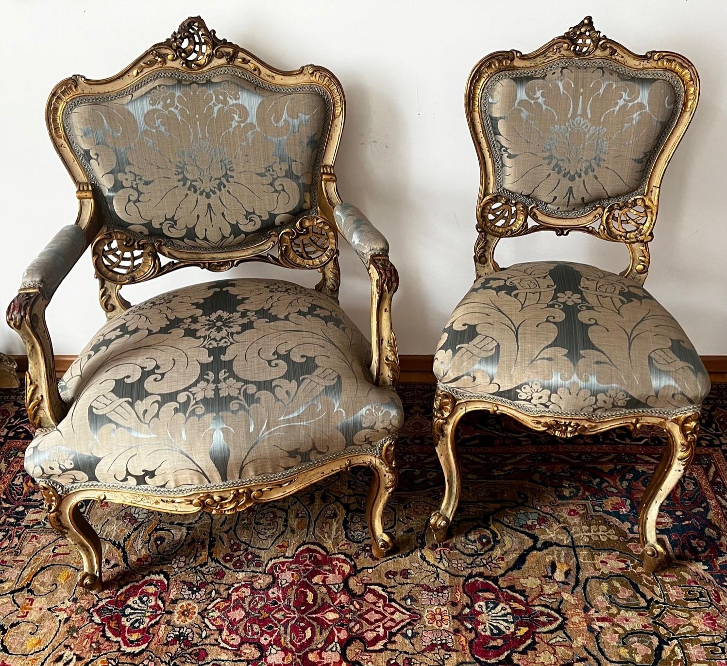 Extraordinary and exquisite set of original Louis XV salon gold gilded chairs with curved wood edges, intricately carved surfaces and Grey Green Patina. One Armchair and one Ladies Lounge chair are executed in the rococo style. They were part of