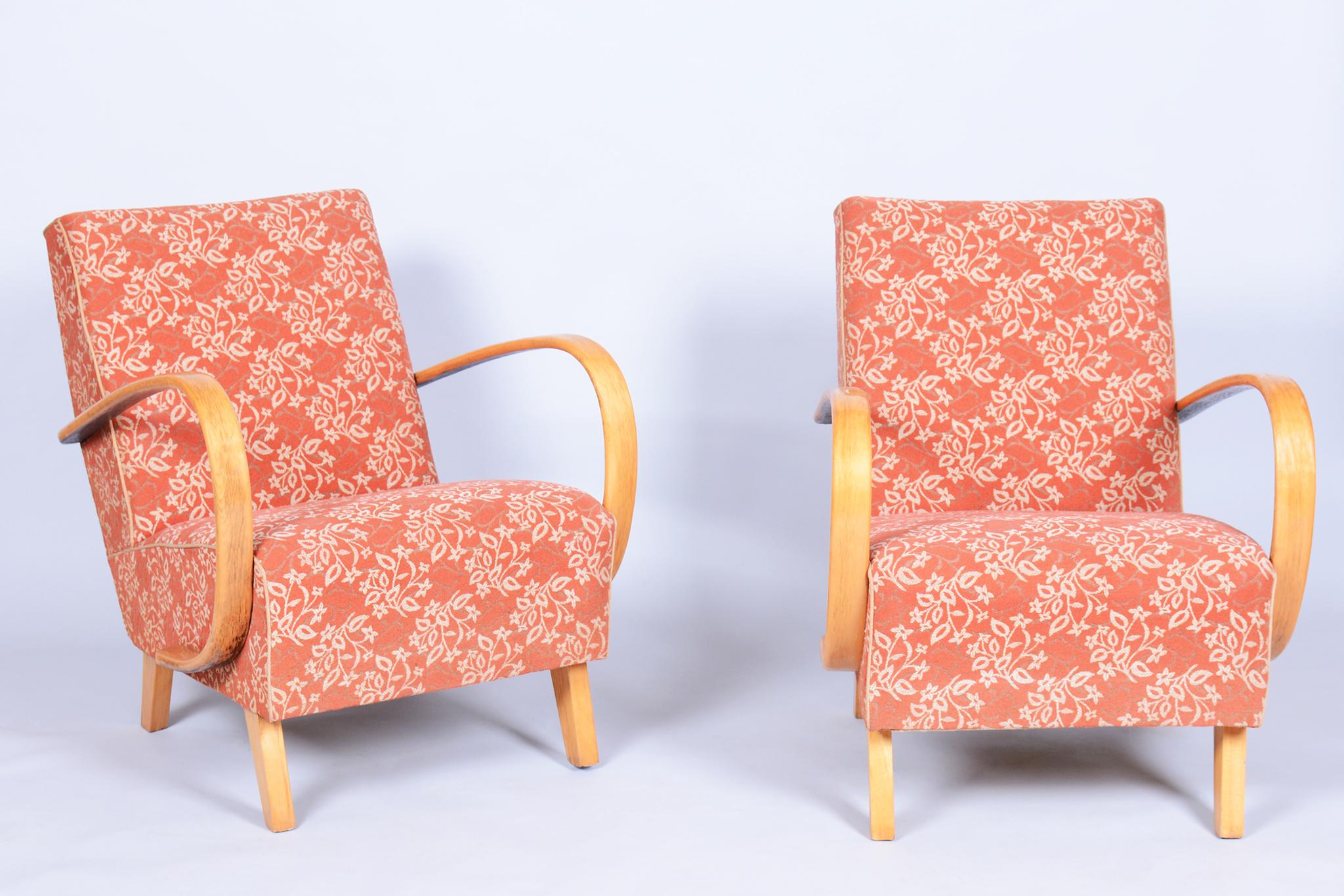 Esta pareja de sillones Art Déco data de principios del siglo XX y está asociada a Jindřich Halabala y UP Závody, famosos por su excelencia en el diseño de muebles checoslovacos. Los sillones presentan reposabrazos de madera maciza de haya curvada,
