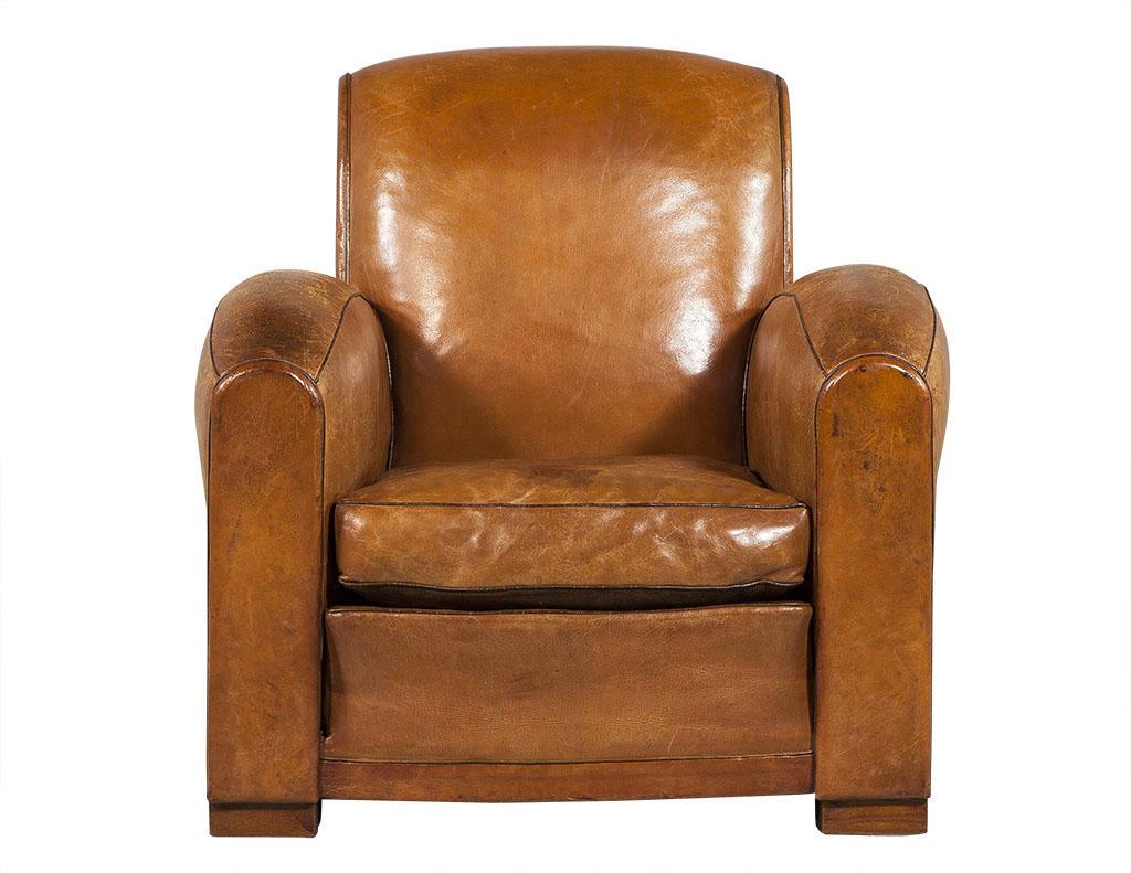 These Art Deco style Gentleman’s chairs are beautifully distressed. Each is upholstered in medium brown leather with dark brown leather piping on the edges for contrast. Sitting atop large wood block feet, each chair is a great fit for a rustic