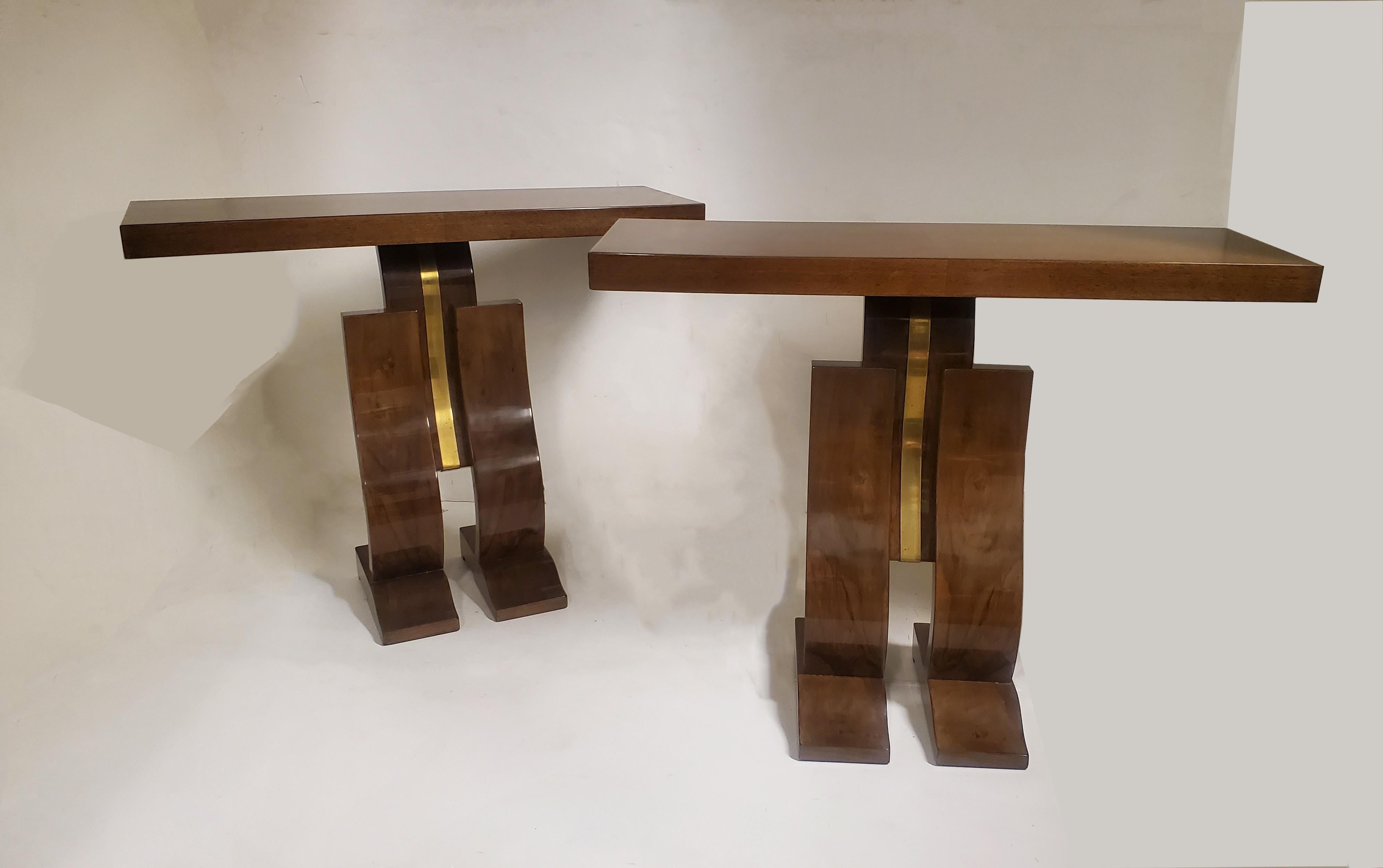 A graceful and elegant pair of French Modern walnut and brass “L” curve consoles. These fabulous original consoles portray simple cubist, angular style, yet are juxtaposed with undulating and curvilinear forms.
Conjoined triple leg design and raised