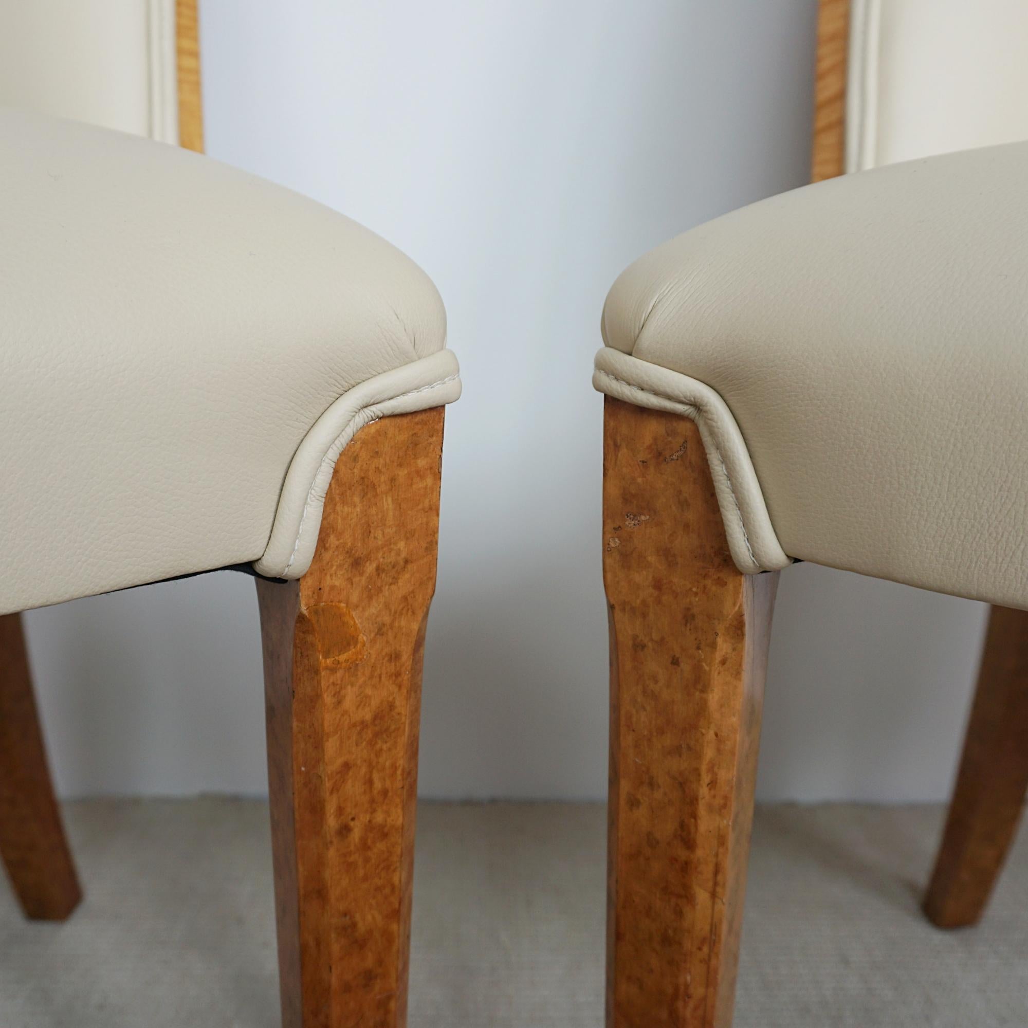 A pair of Art Deco cloud chairs by Harry & Lou Epstein. Burr walnut veneered backs with Trompe-l'œil burr walnut legs. Re-upholstered in cream leather. 

