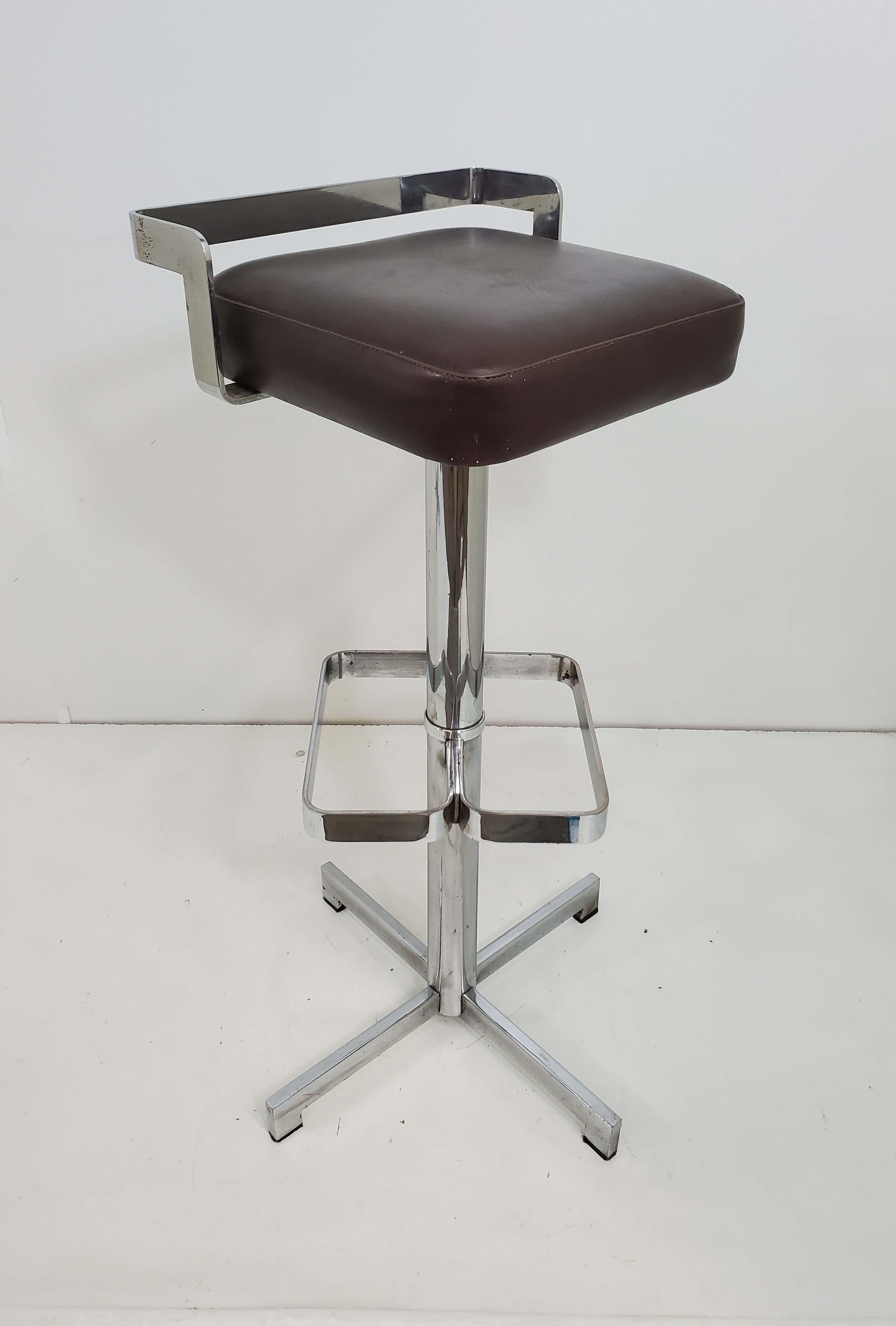 Pair of vintage Mid-Century Modern bar stools feature unique architectural chrome plated frames topped by a 
brown, dark expresso colored upholstered vinyl seat.
 Sleek design with an angular backrest, foot rest, and ending with a supportive 
