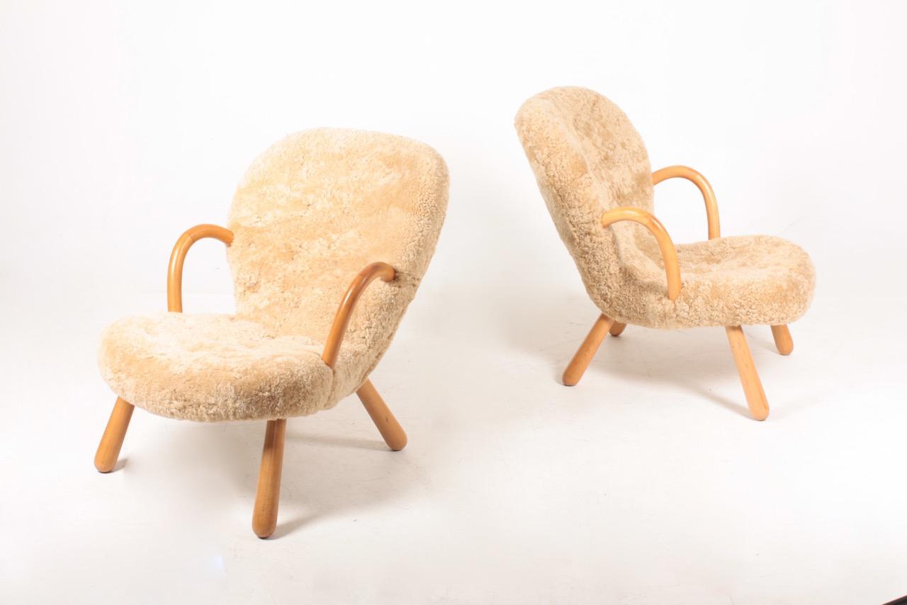 Pair of lounge chairs with round armrests and legs of patinated beech. Seat and back upholstered with sheepskin. Designed and made in Denmark, great condition.