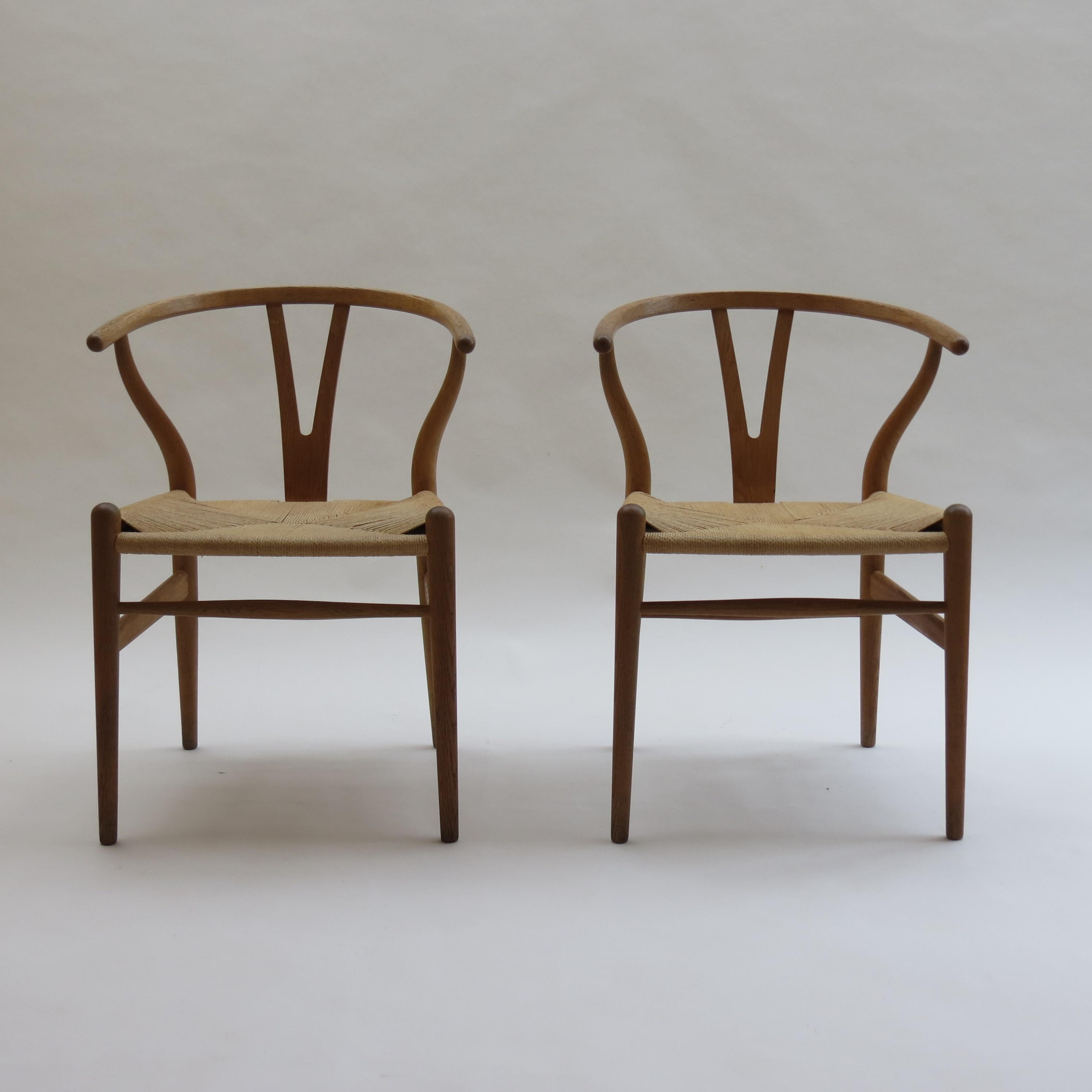 Pair of vintage original wishbone chairs, designed by Hans J Wegner and manufactured by Carl Hansen, Denmark.

Made from solid oak with original oiled finish. Paper cord seat.

Both chairs retain original paper label to the underside.

In good