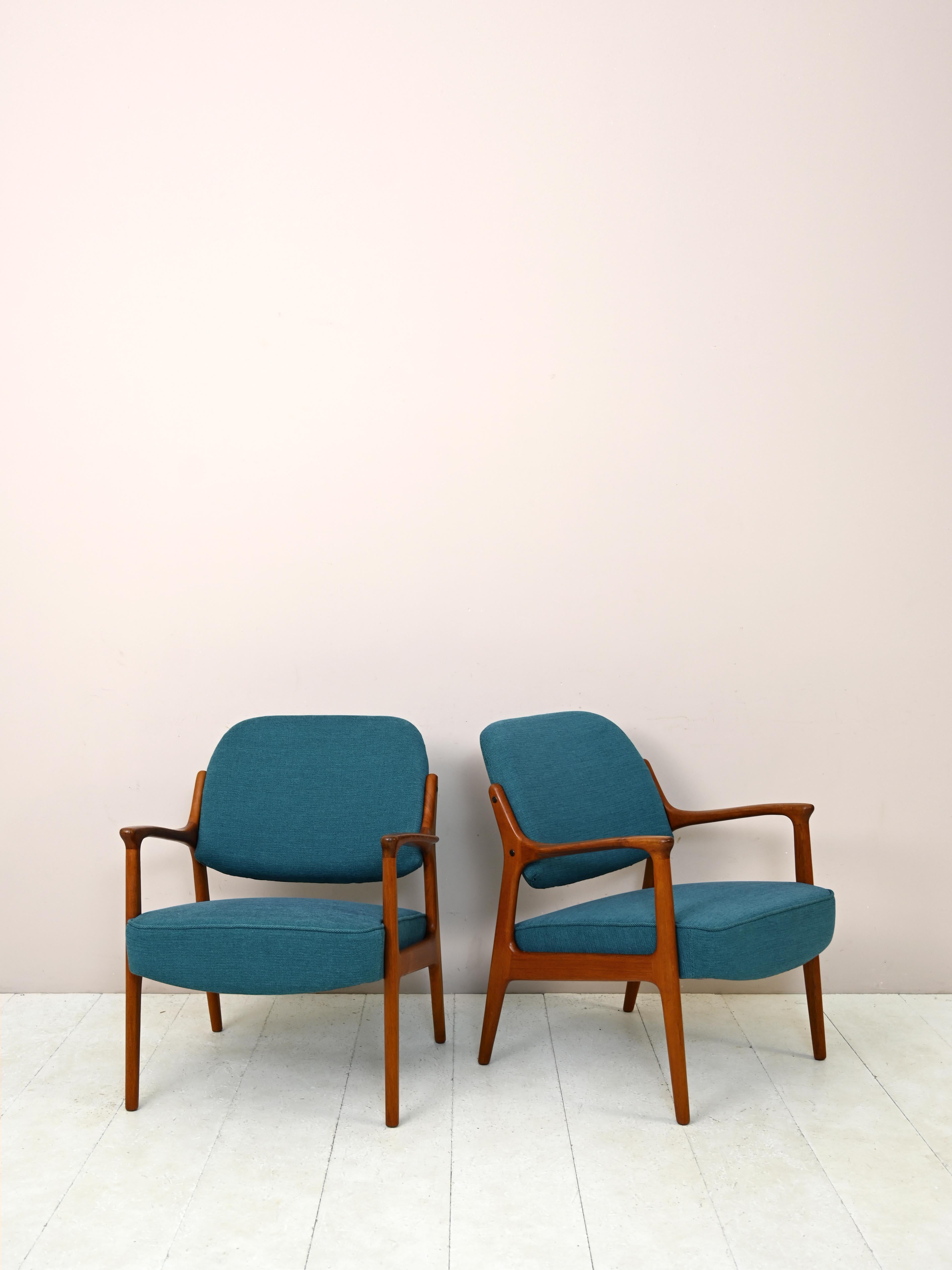 Pair of 1960s modernist armchairs.

These armchairs with essential lines, typical of mid-century Scandinavian design, feature a teak wood frame with armrests and a comfortable upholstered seat reupholstered with brass-blue fabric.
Perfect for