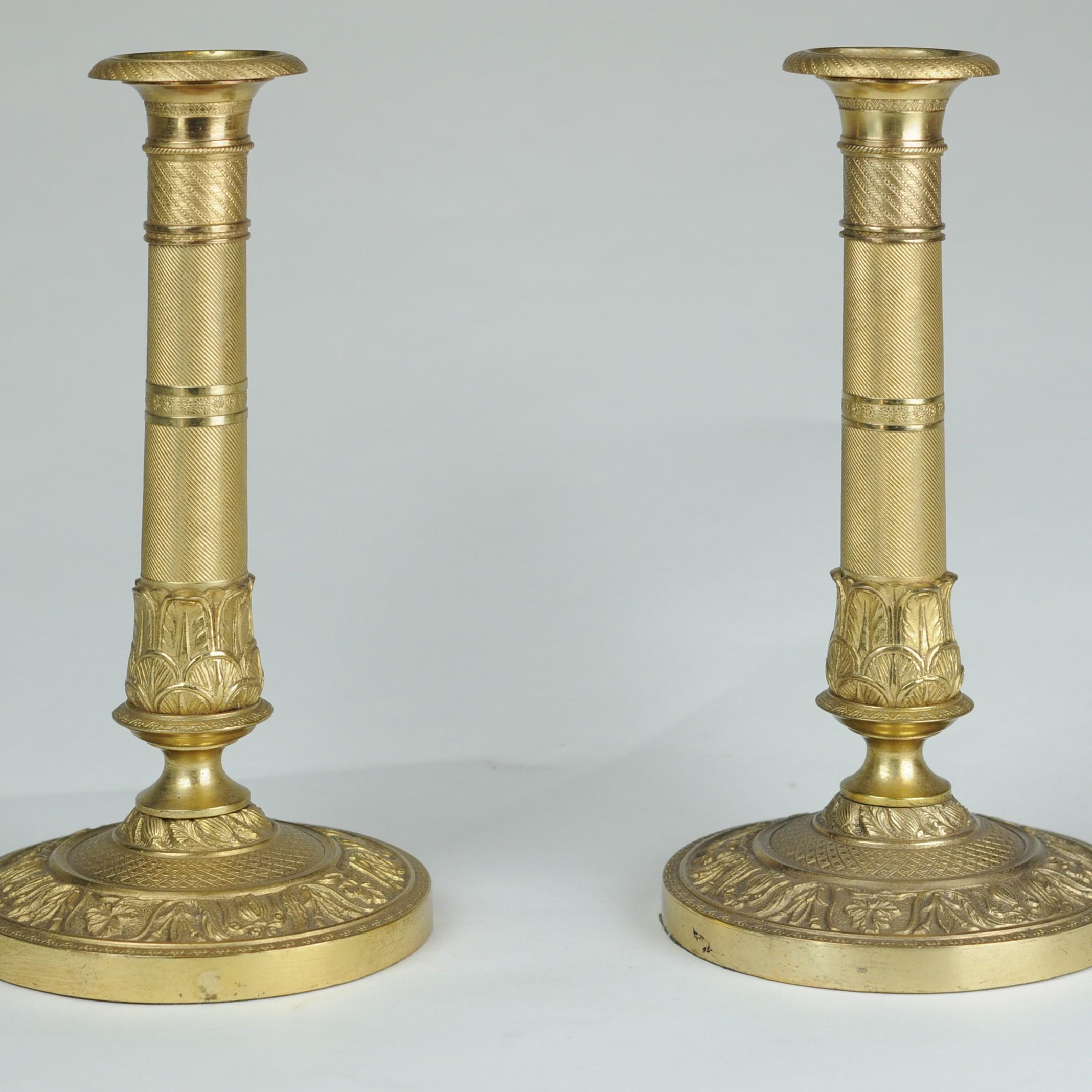 A fine pair of early 19th century ormolu candlesticks decorated with crisp, engine-turning throughout and retaining the original sconces. Unusually with weighted bases, possibly indicating English manufacture.