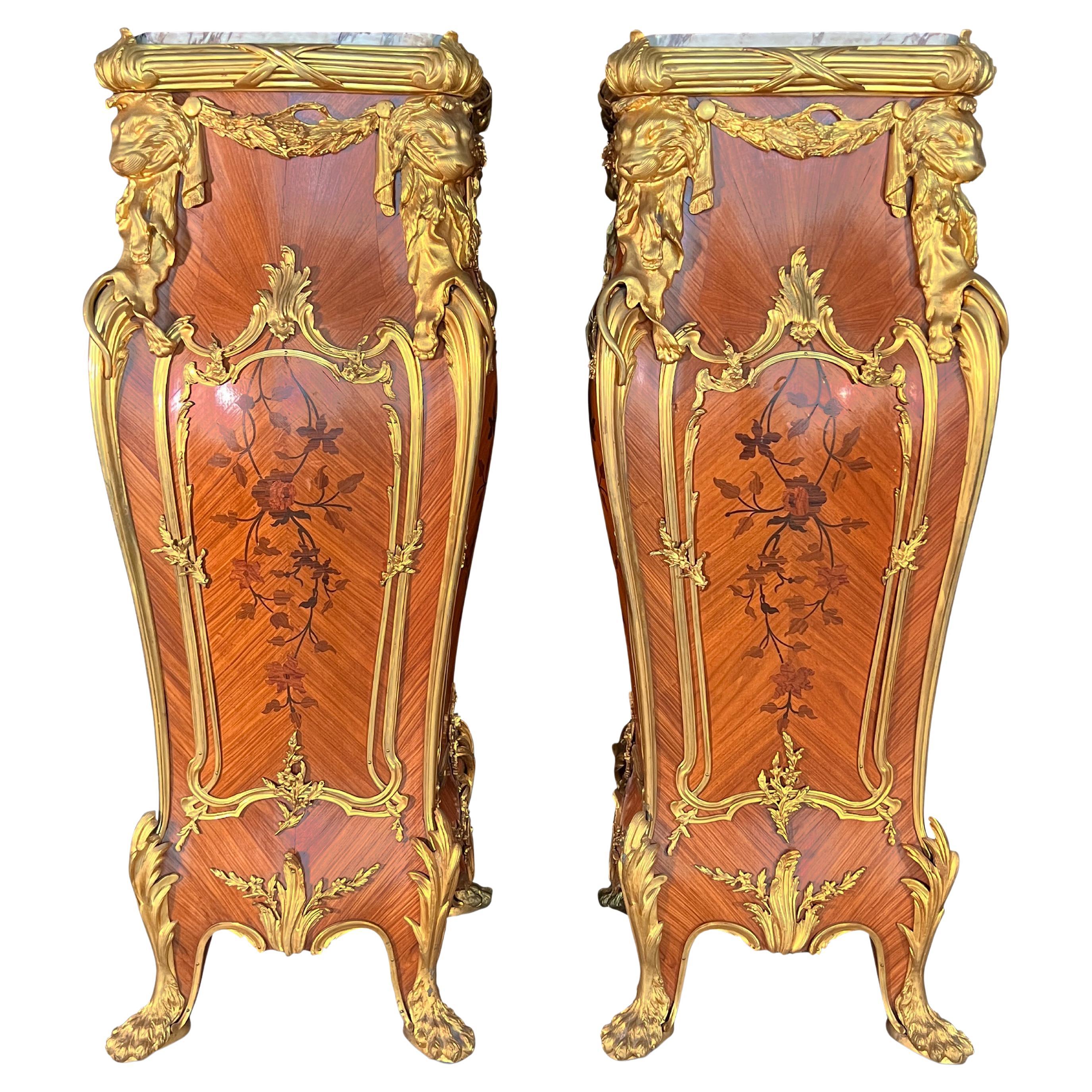 A pair of ormolu mounted marquetry pedestals. After a model by Francois Linke.
Each with a marble top above bombé sides inlaid with loose floral bouquets, the angles mounted with lion-pelts suspending laurel swags and drapery, on short