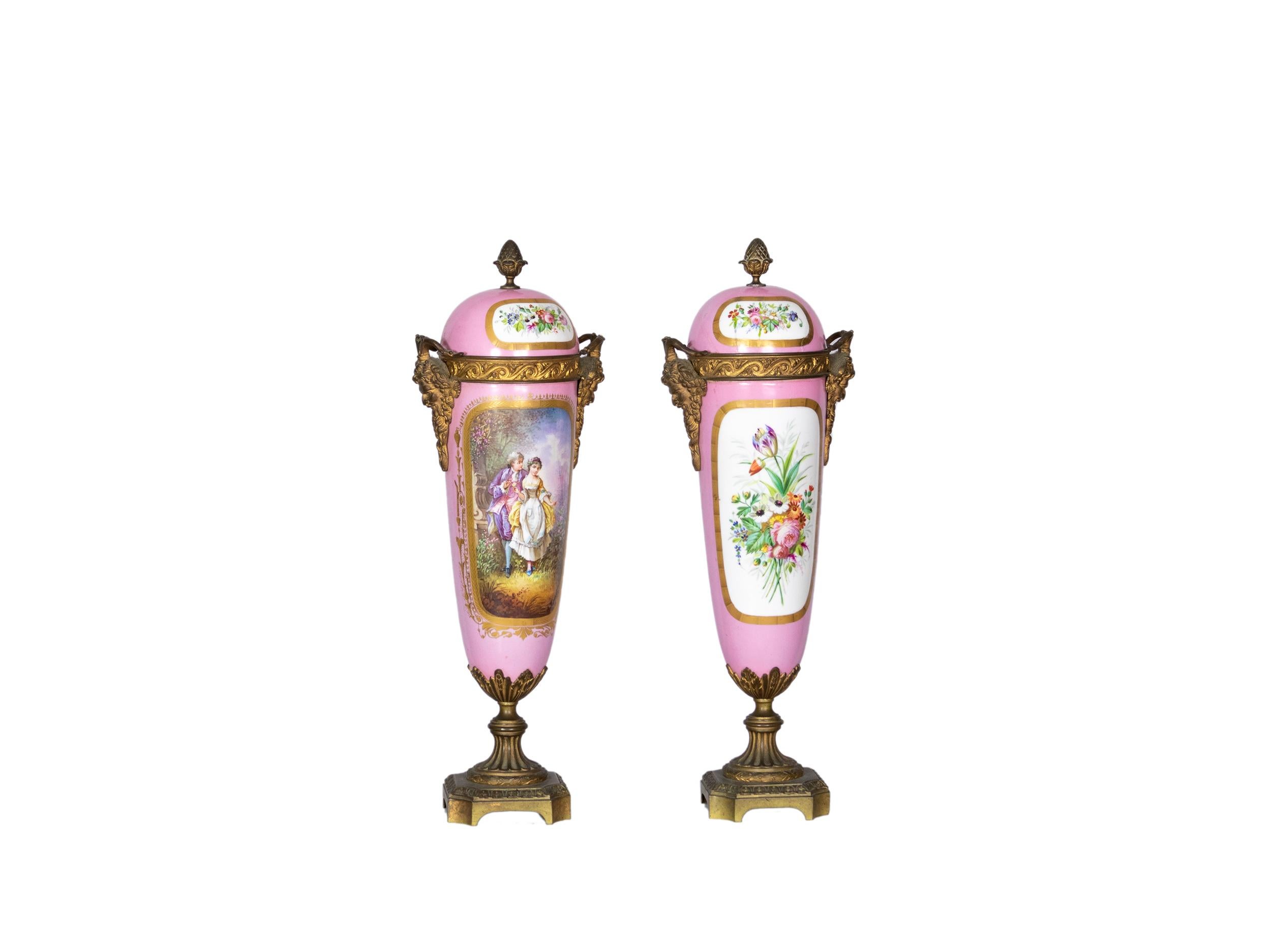Pareja de urnas francesas de Sevres del siglo XIX con tapa, finamente montadas en ormolu y pintadas a mano con composiciones florales y escenas románticas. 
El cuerpo de porcelana rosa suave está adornado con delicados ramos de flores e imágenes