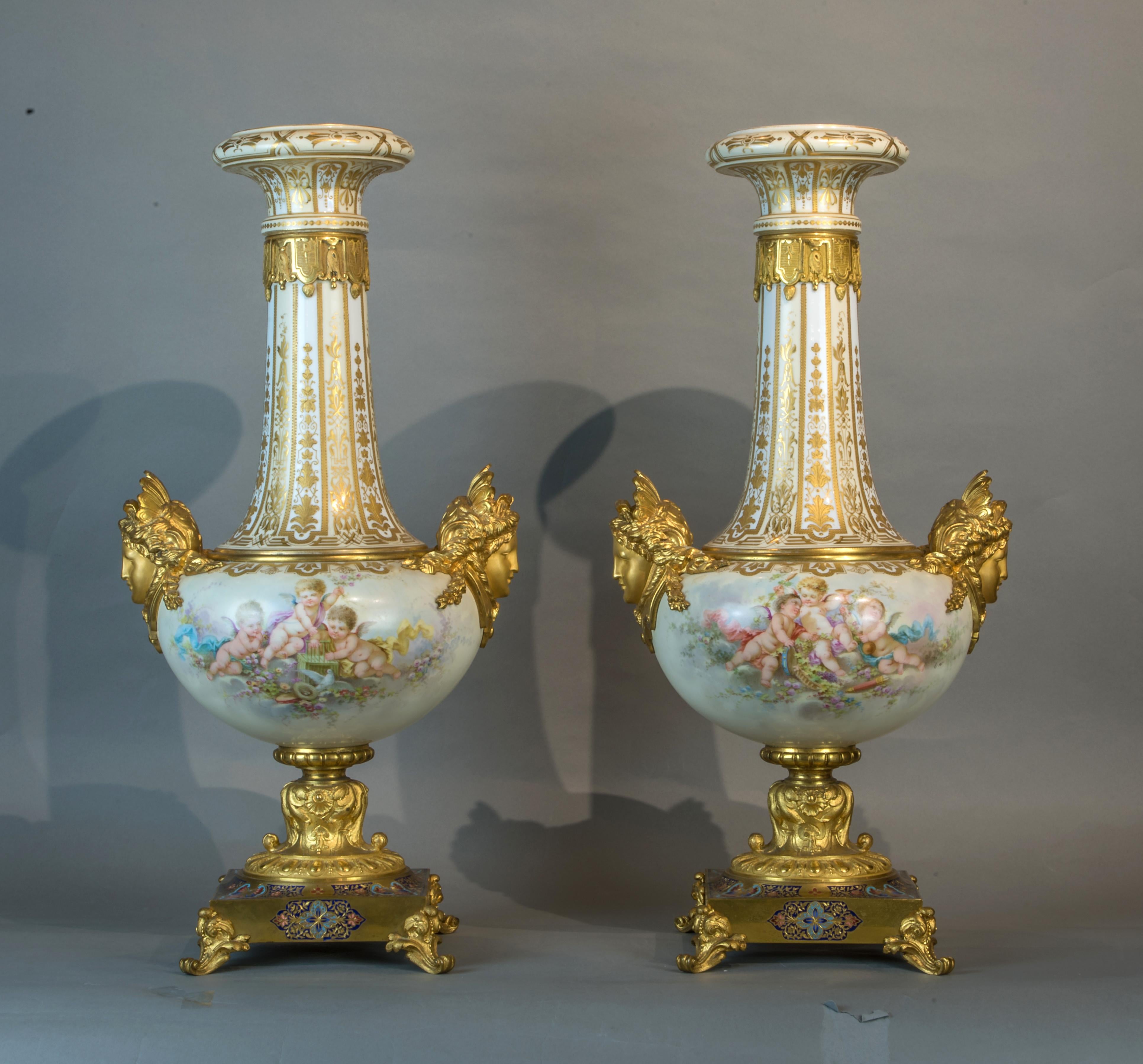 Fabulous pair of fine quality bronze-mounted Sèvres-style porcelain vases on bronze base. The hand-painted depiction of cherubs and floral motifs surrounded by raised gilding. The porcelain body flanked by maiden mask handles, four footed,