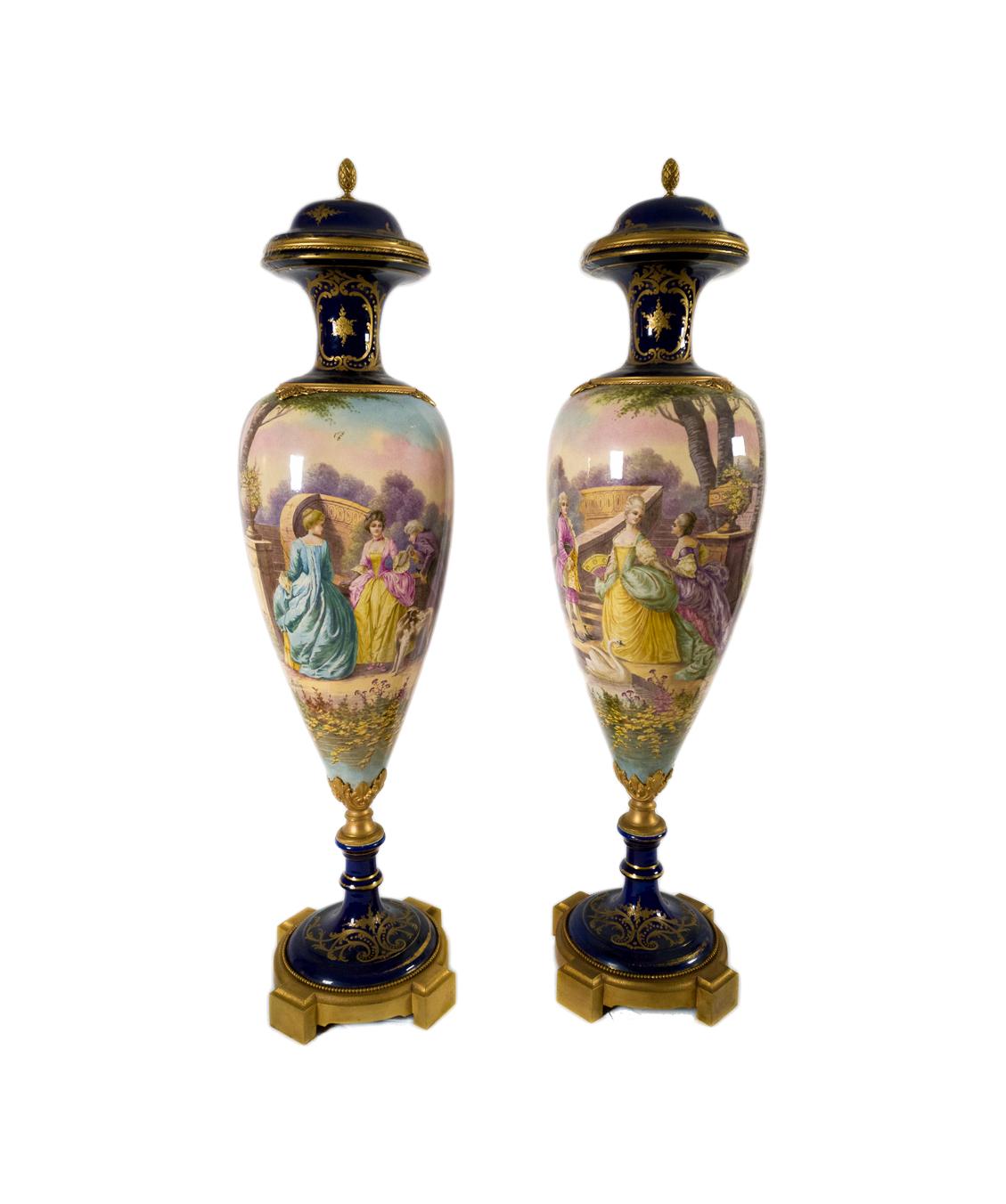 Coppia di vasi in porcellana blu cobalto montati su ormolu di Sèvres con supporti in bronzo dorato, decorati con fiori in smalto oro rococò e volute floreali policrome, decorazione galante nel rigonfiamento centrale con scena palaziale dipinta a