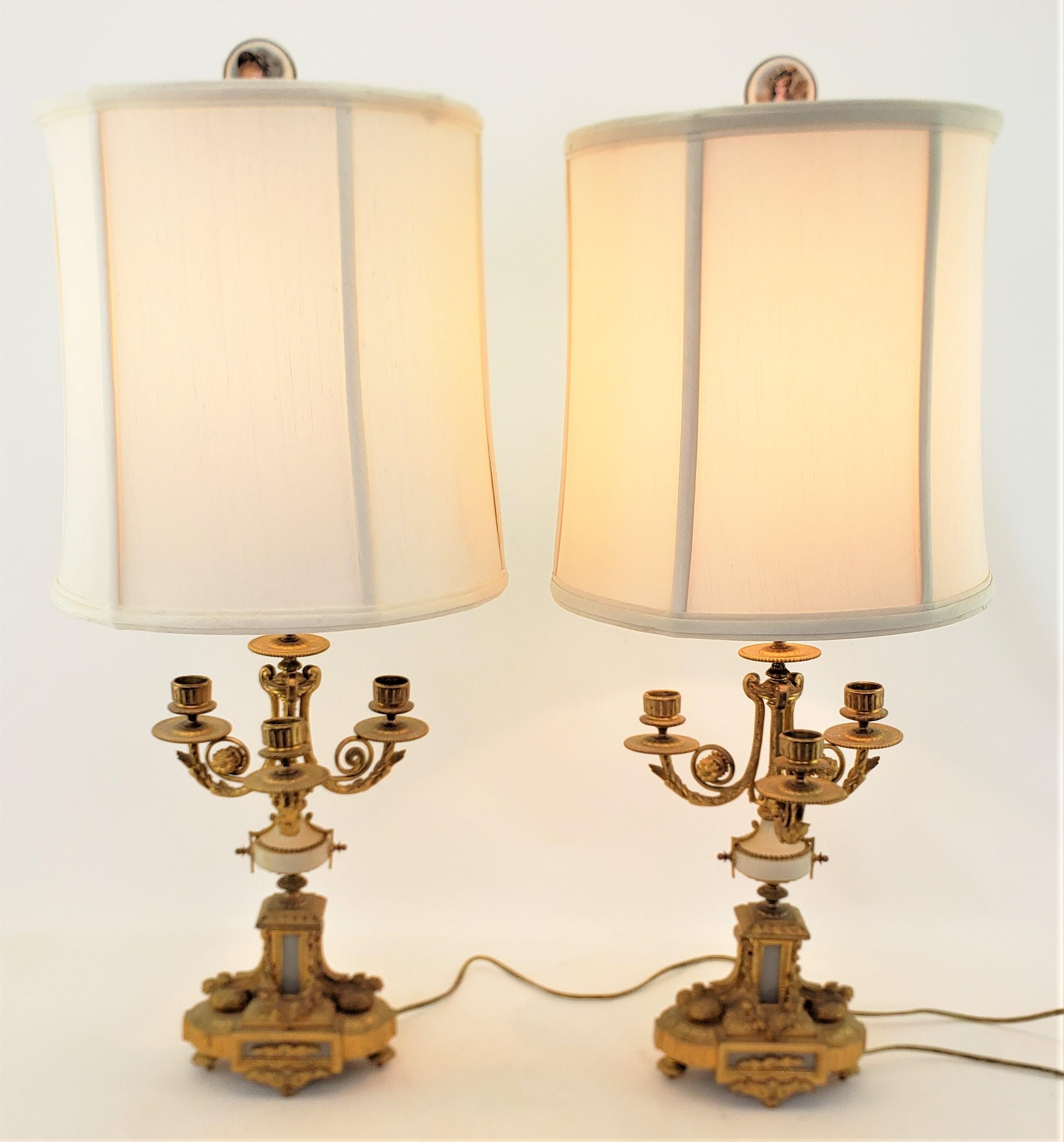 This pair of antique converted candelabra lamps are unsigned, but presumed to have originated from France and date to approximately 1880 and done in a Renaissance Revival style. The candelabras are composed of ornately cast and gilt finished bronze