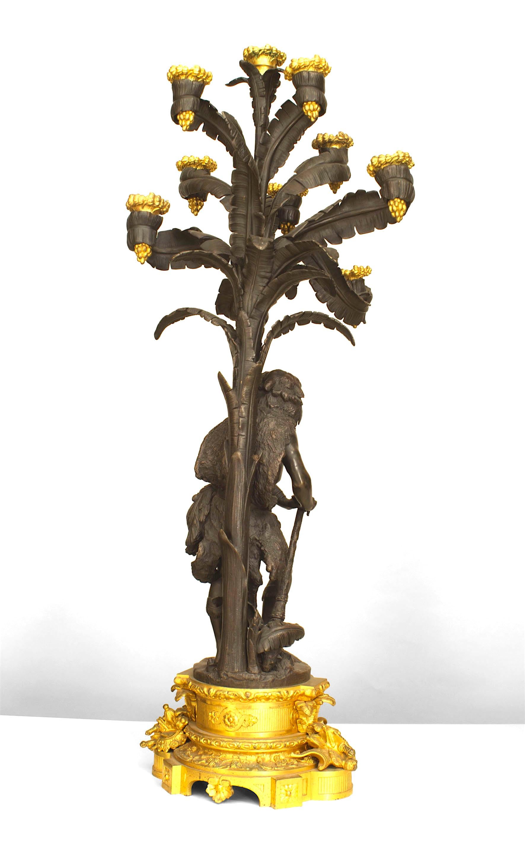 Pair of French Napoleon III gilt and patinated bronze ten-light candelabra with a traditionally dressed man and woman under palm trees mounted on bases.