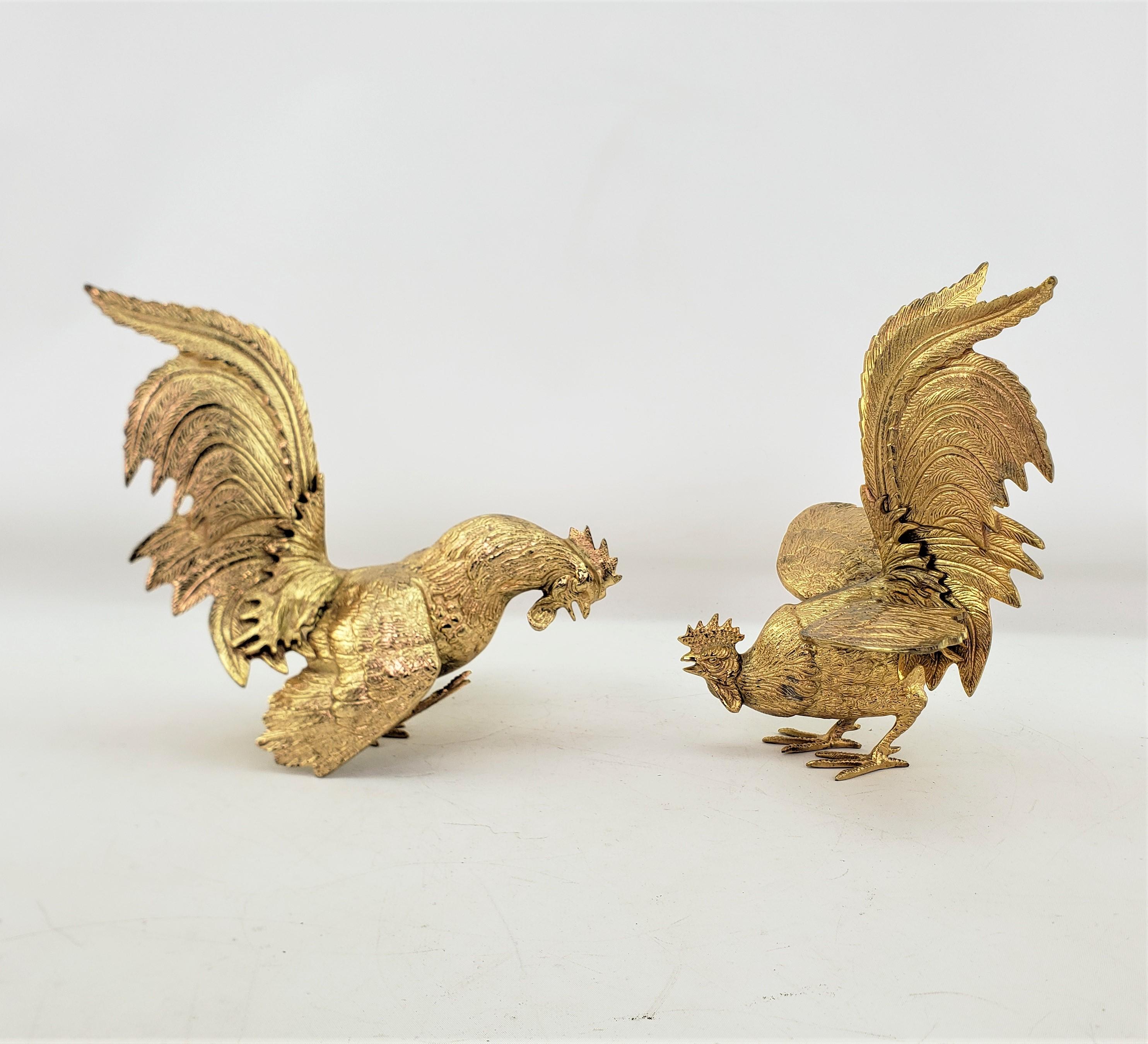 This pair of ornately cast fighting roosters are unsigned, but presumed to have originated from Italy and date to approximately 1920 and done in a Victorian style. The well cast roosters are composed of cast metal, with a gilt plated finish. One