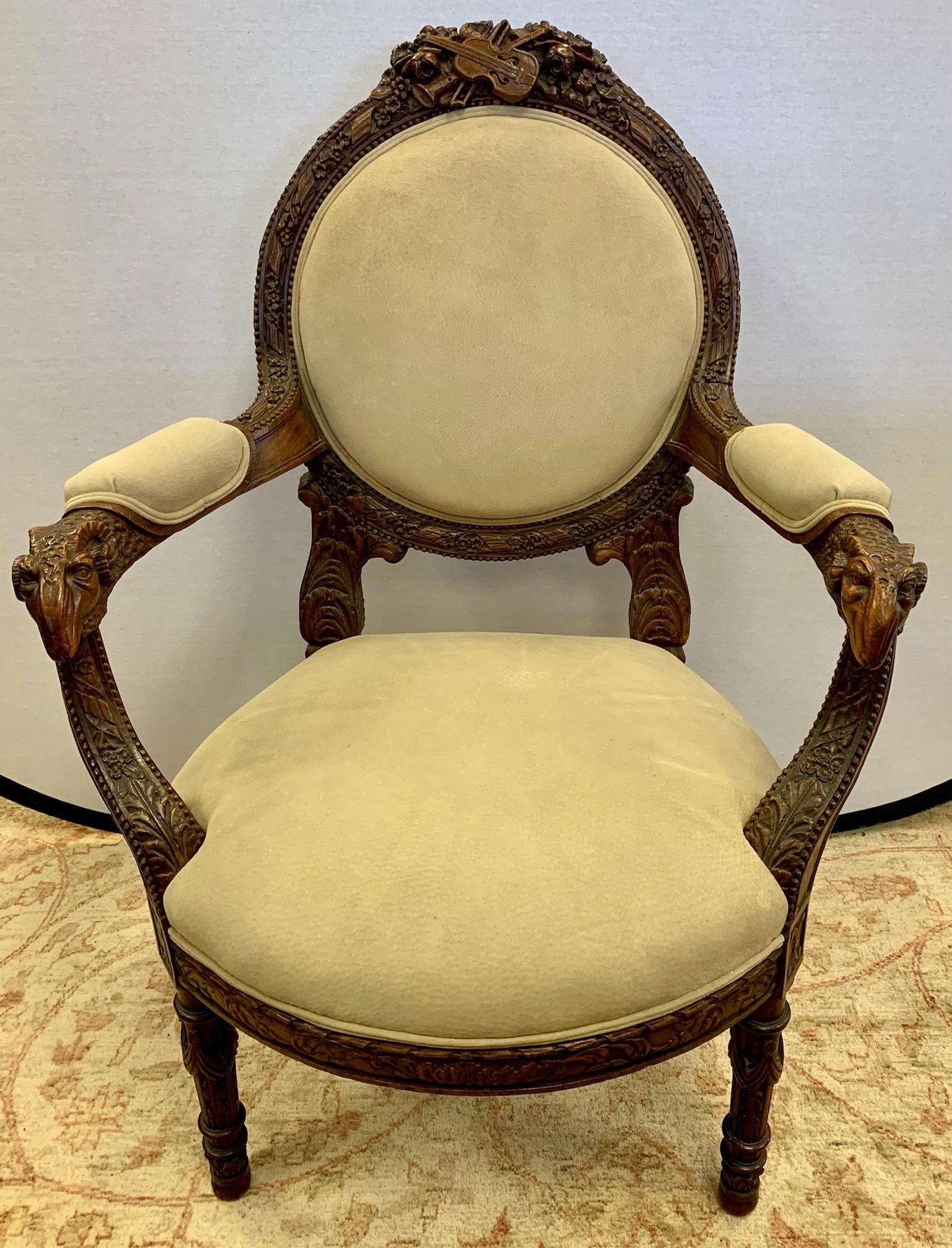 Magnificent French walnut armchairs featuring elaborate carved details including the carved crest and ram's head arms. See pictures for details. Upholstered in a neutral suede fabric.