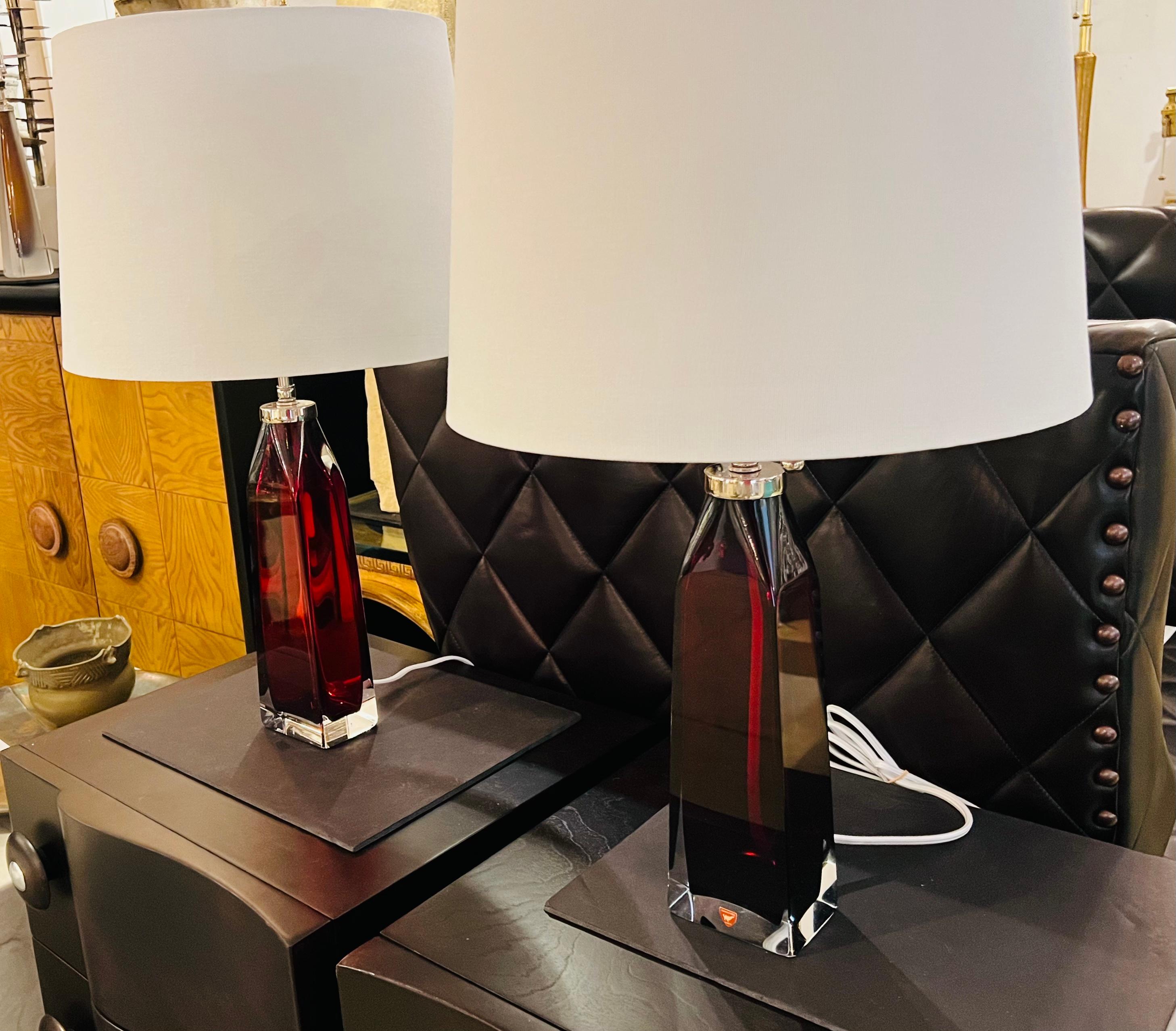 Pair of luxurious thick crystal tables lamps in a deep ruby red color and polished nickel fittings and sockets with white silk cords. Rewired. White linen shades 14” Wx10” H