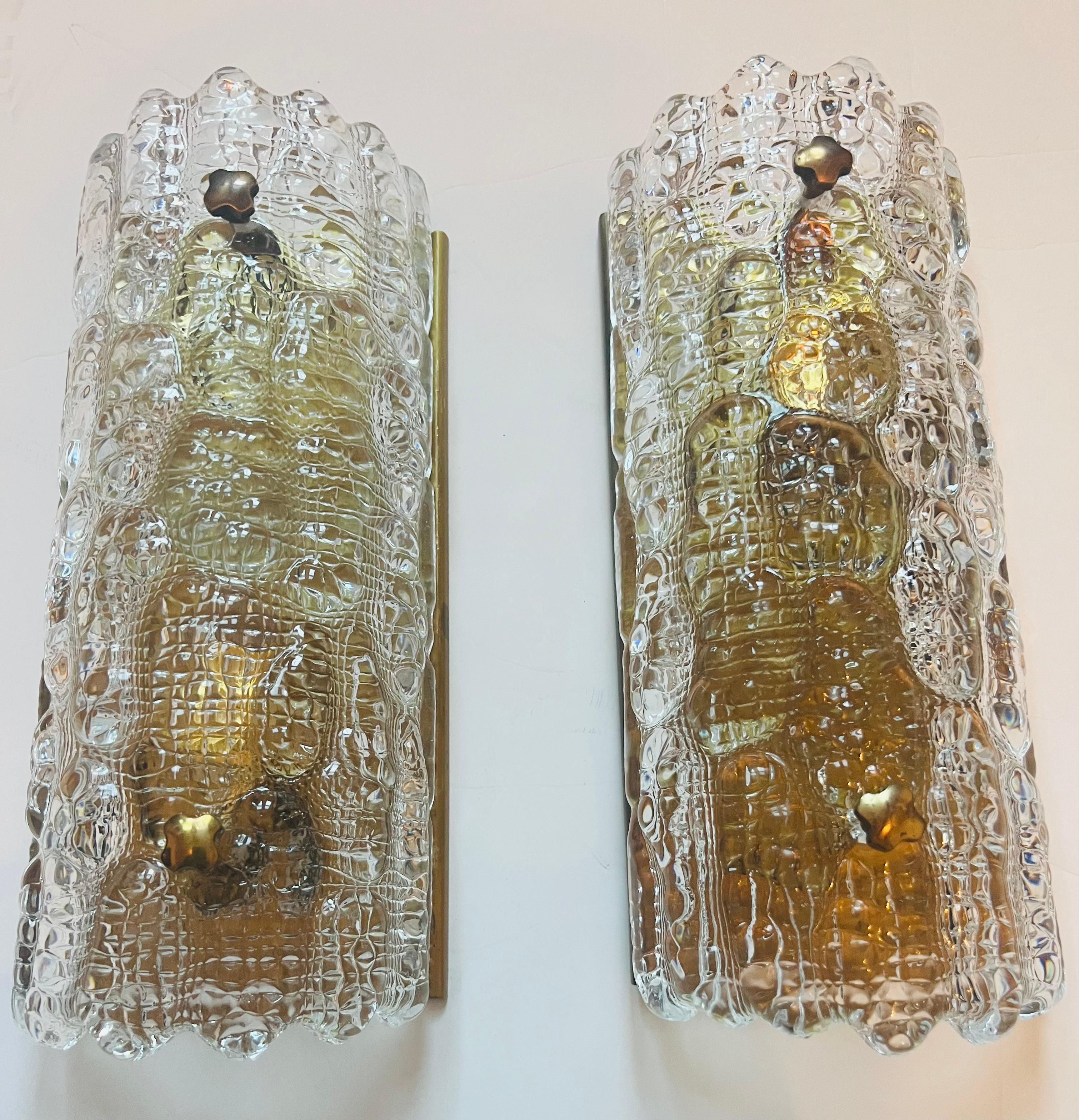 A luxurious pair of 1950s Swedish crystal wall lamps with thick glass shades and aged brass fixtures and decorative fittings by Carl Fagerlund for Orrefors. Rewired. Candelabra socket.