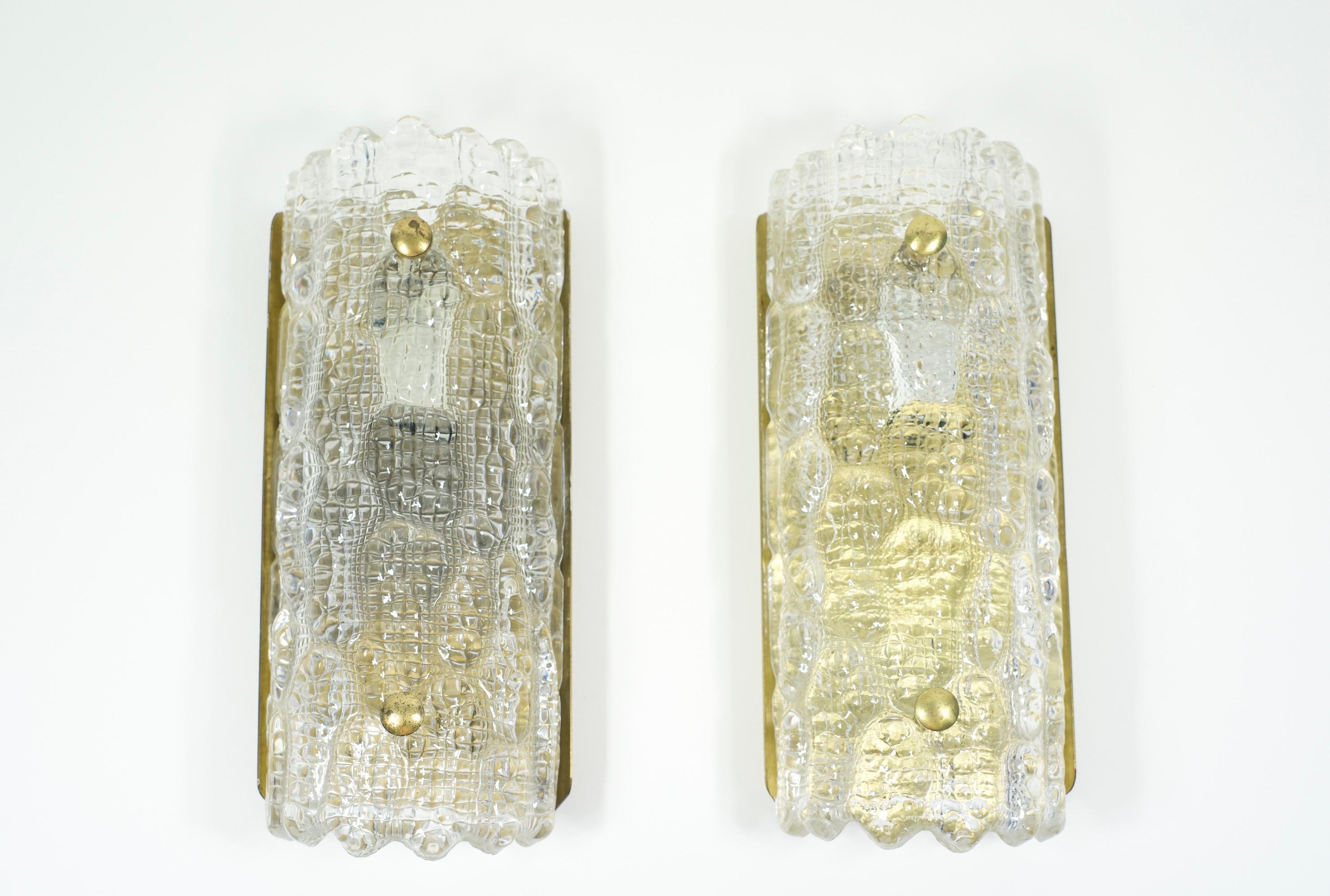 Pair of Orrefors clear glass sconces, crocodile pattern, glass shades are resting on a brass frame with brass fasteners.

Rewired for the US.

Holds one candelabra bulb each.