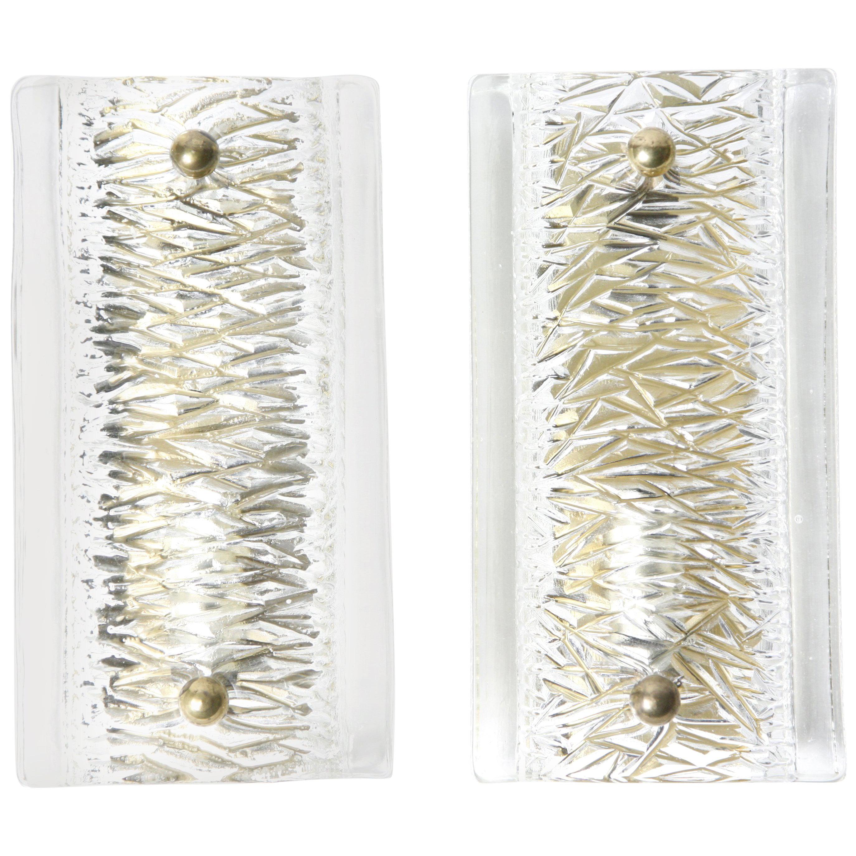 Pair of Orrefors clear cast crystal glass sconces with reflections in rainbow colors, smooth surface outer glass and an inside pattern, glass shades are resting on a brass frame with brass fasteners.
Hold one candelabra bulb each.
