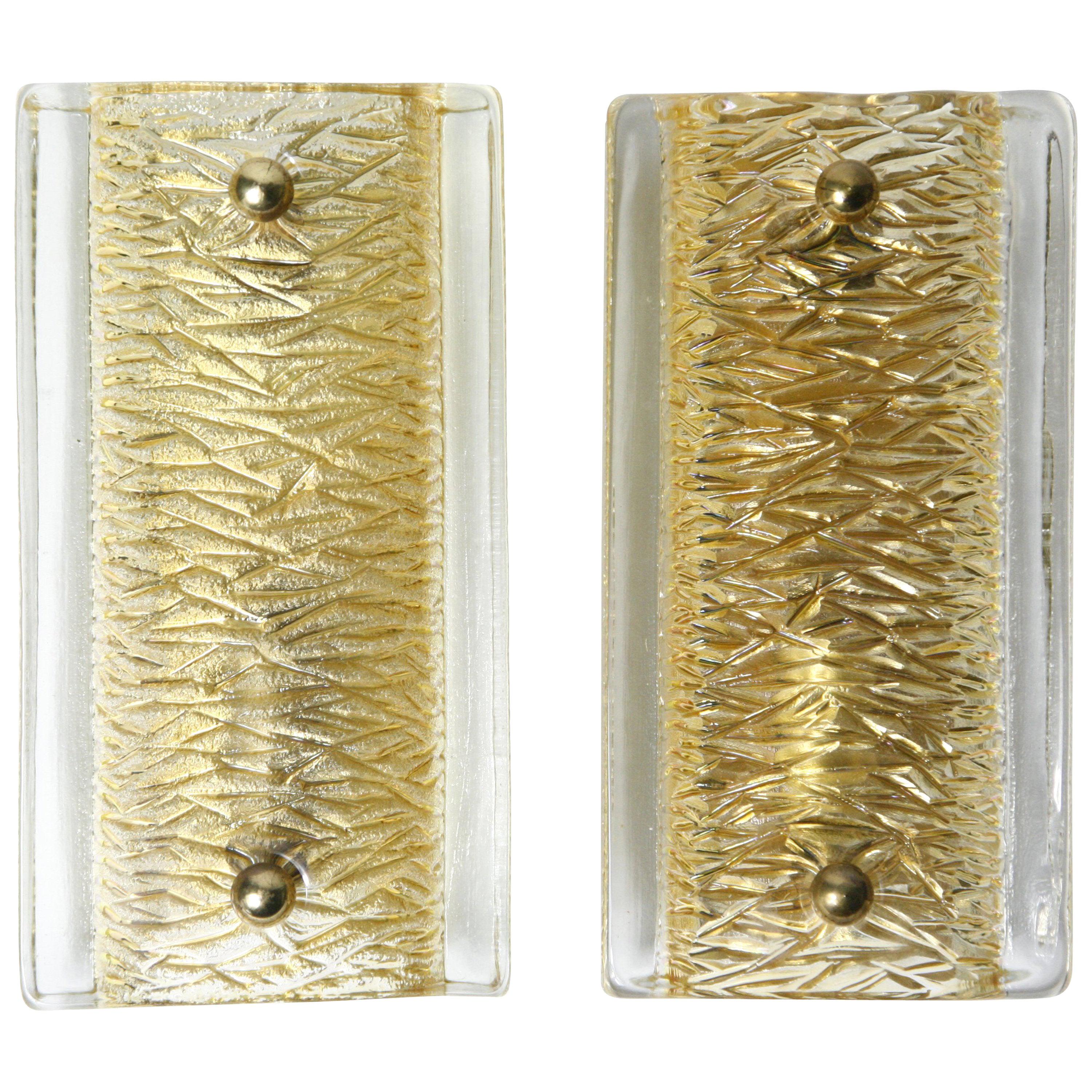 Pair of Orrefors amber colored glass sconces Sweden 1970, smooth surface outer glass and an inside pattern, glass shades are resting on a brass frame held with brass fasteners.
Hold one candelabra bulb each.