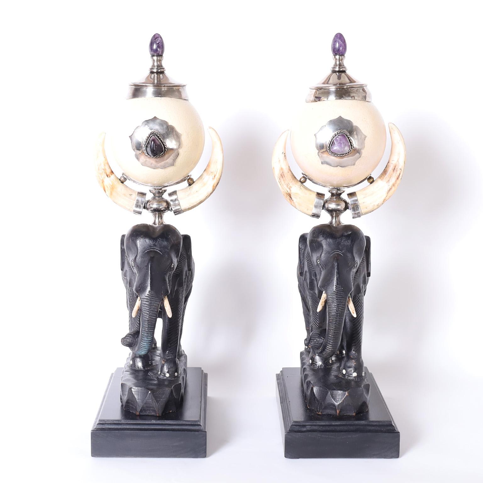 Mid-century pair of Anthony Redmile urns crafted with an eccentric array of materials featuring amethyst stone, ostrich eggs, boar tusks and carved ebony all in a dramatic composition of form and function. Signed 