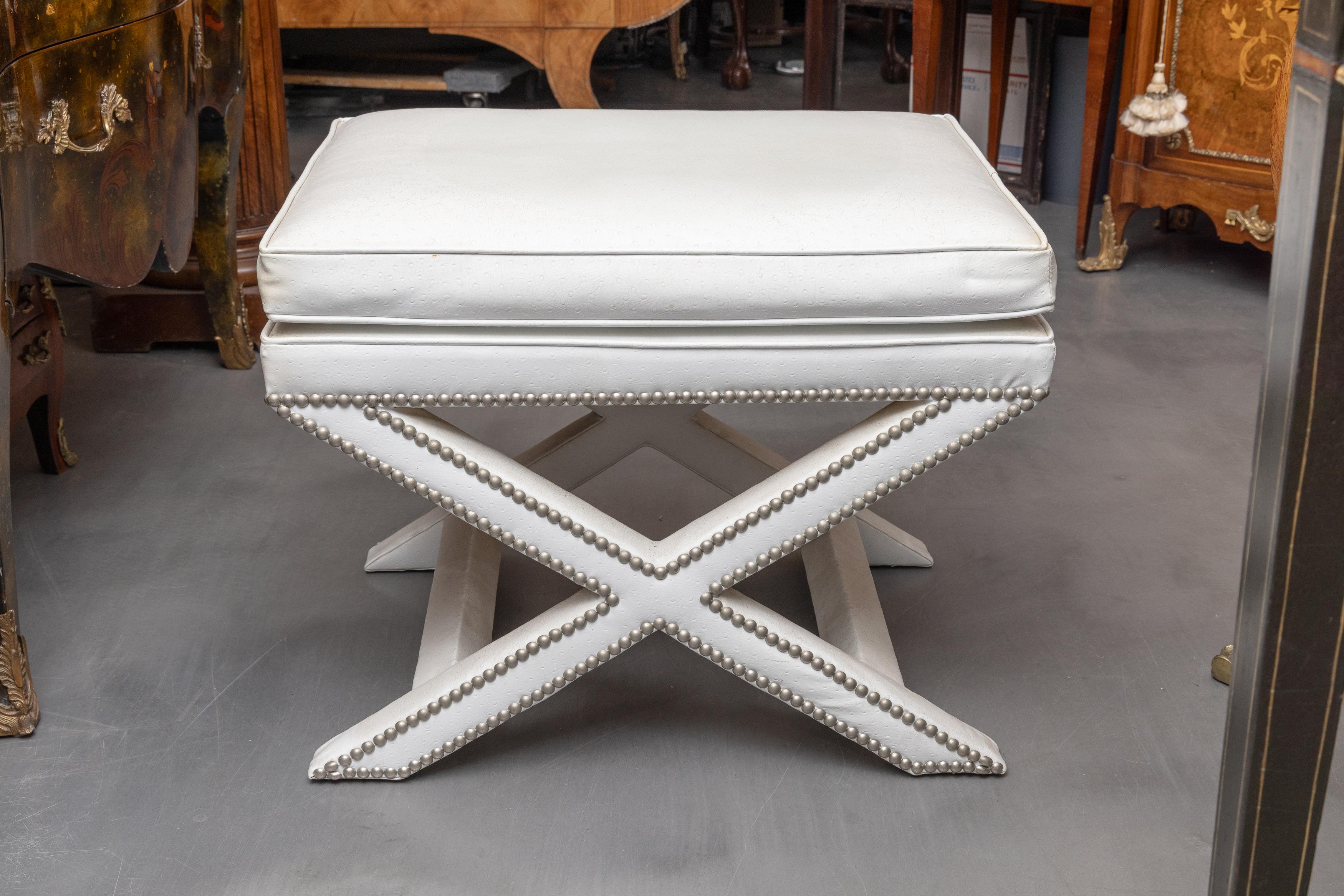 This is a stylish pair of white ostrich leather X benches with attached cushion above silver-studded X base.