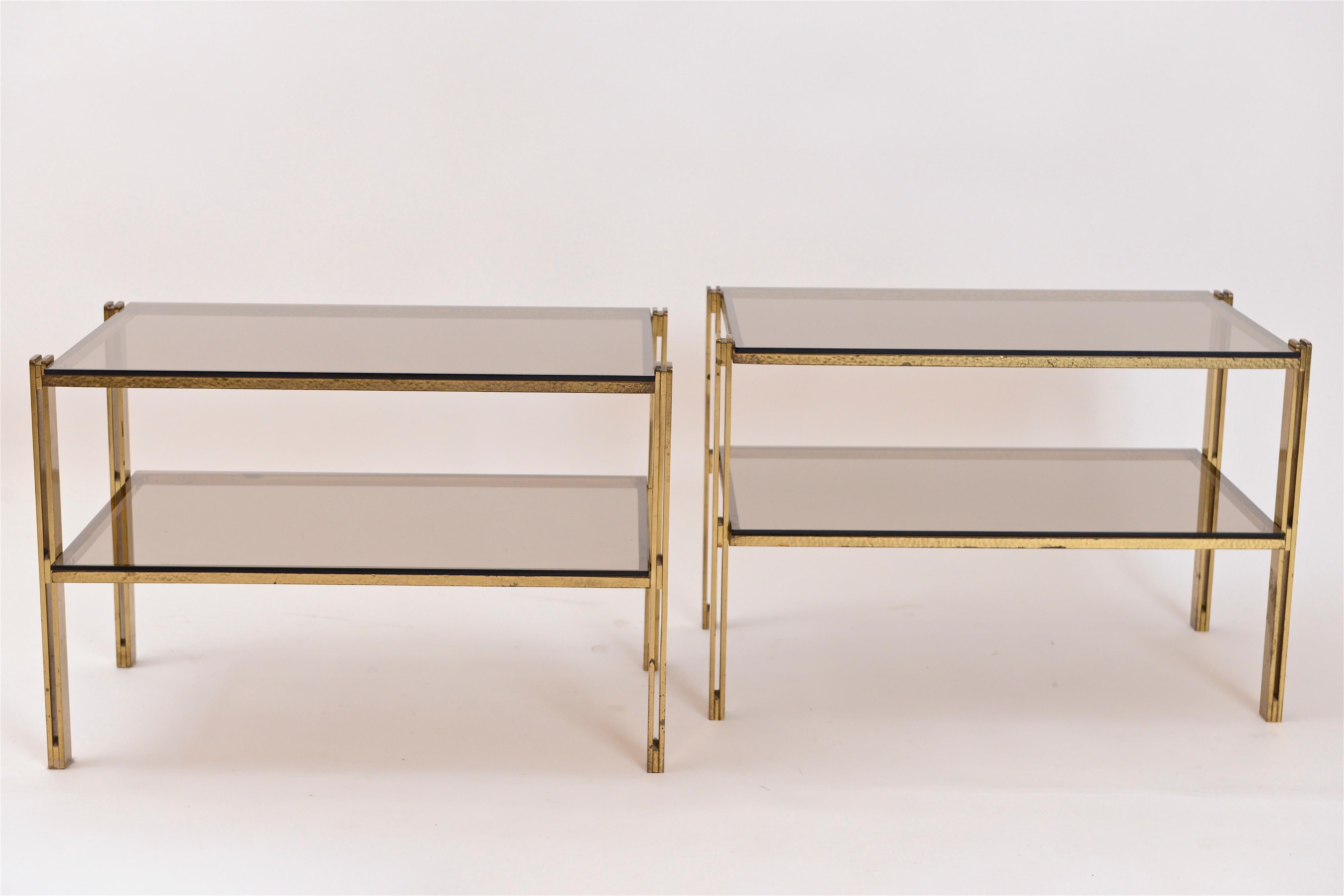 A fantastic pair of brass and fumé glass side tables attributed to Osvaldo Borsani. These two-tiered tables are constructed of the highest quality materials…solid hammered brass and original fumé glass inserts.