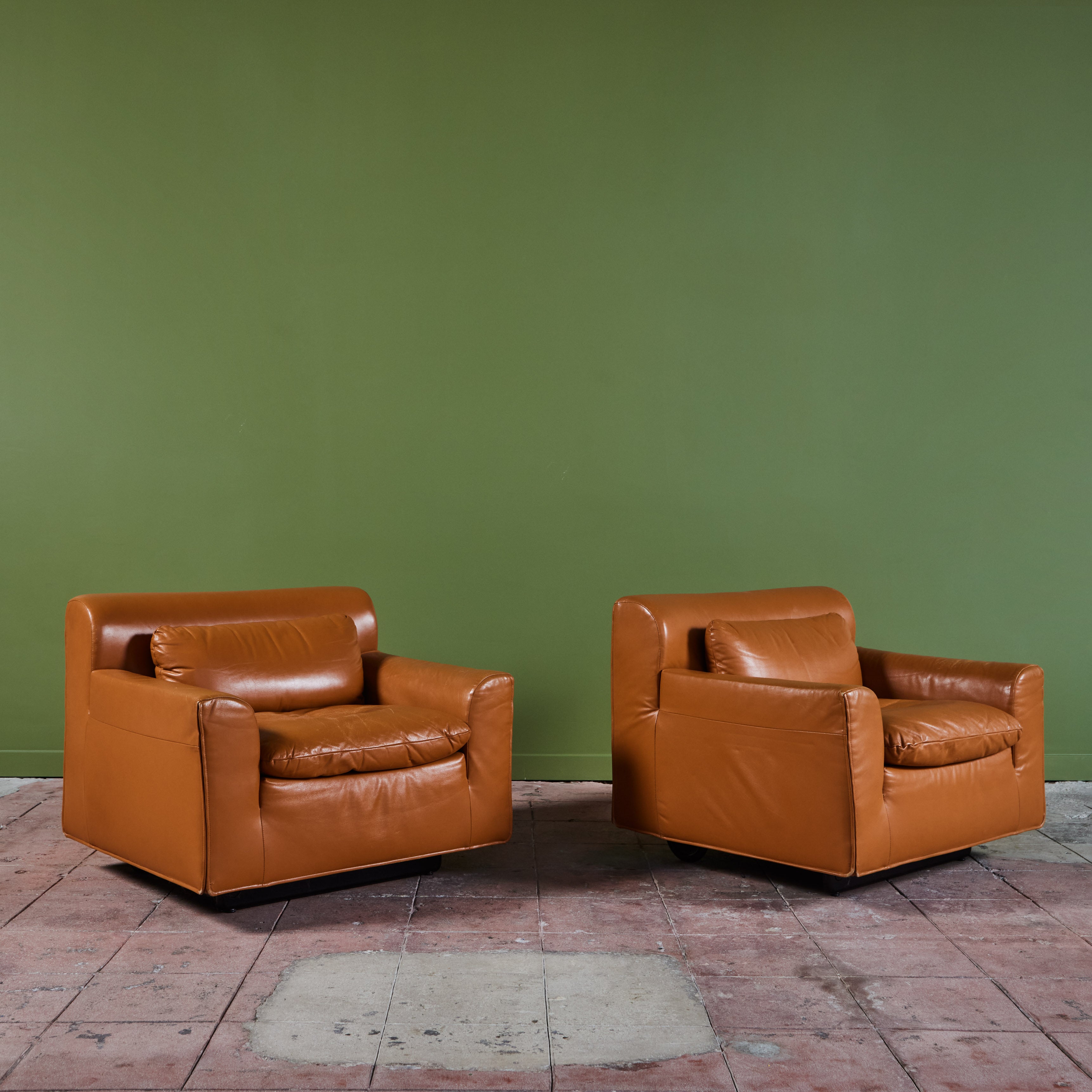 Pair of leather lounge chairs by Otto Zapf for Knoll International, c.1990s, USA. The plush lounge chairs feature original deep camel leather upholstery and cushions. The armrests and backrests have a slight rounded curve and stitched detailing. The