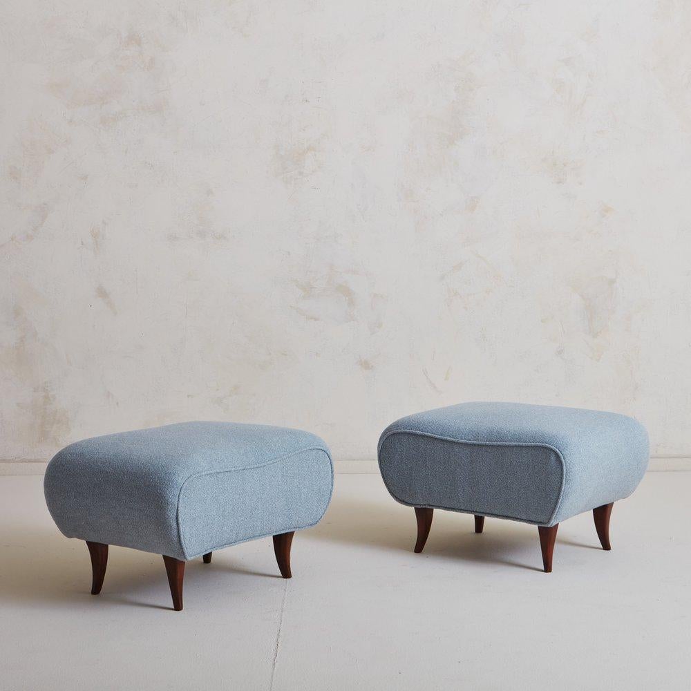 A darling pair of vintage ottomans freshly reupholstered in a light blue wool blend fabric with single welt detailing. They stand on flared, tapered wooden legs which were refinished and stained. Sourced in Italy, 20th century.