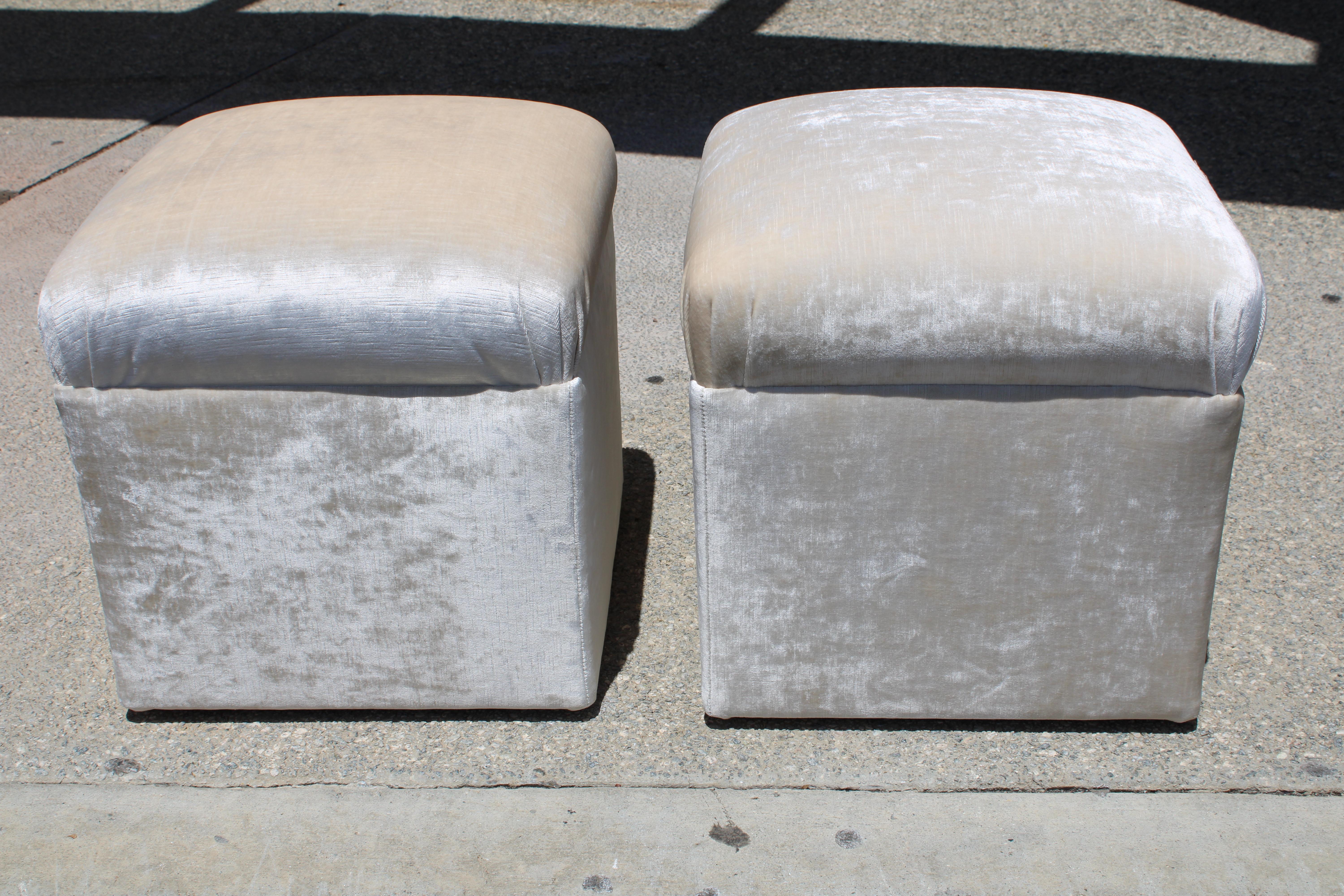 Pair of ottomans on rollers which we had professionally reupholstered in a shiny velvet fabric. Ottomans measure 17