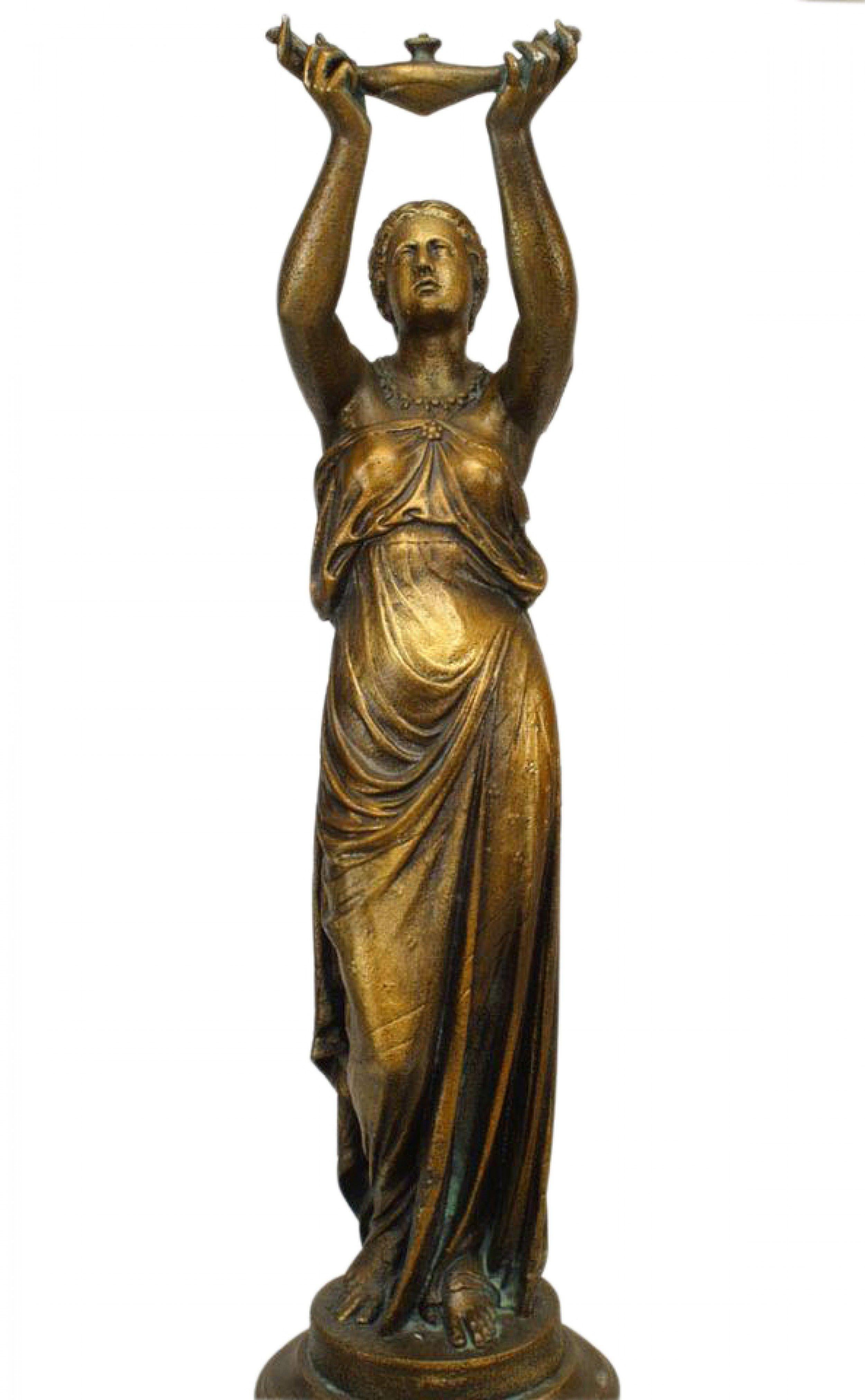 PAR de figuras femeninas de hierro pintado al aire libre (finales del siglo XIX) con forma clásica y tamaño natural, que sostienen una pequeña lámpara de Aladino sobre sus cabezas y se apoyan en pedestales redondos. (atr. Val D'Osne) (PRECIO POR