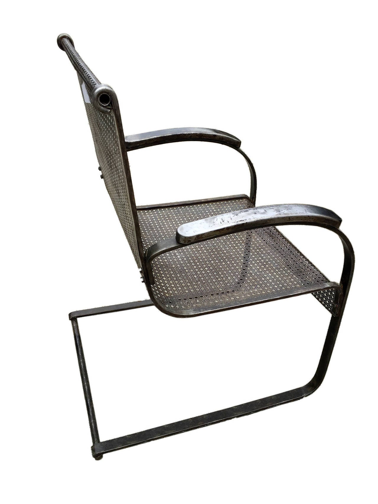 Unusual pair of iron armchairs with perforated sheet used as support for back and seat, equipped with armrests. USA, circa 1930.