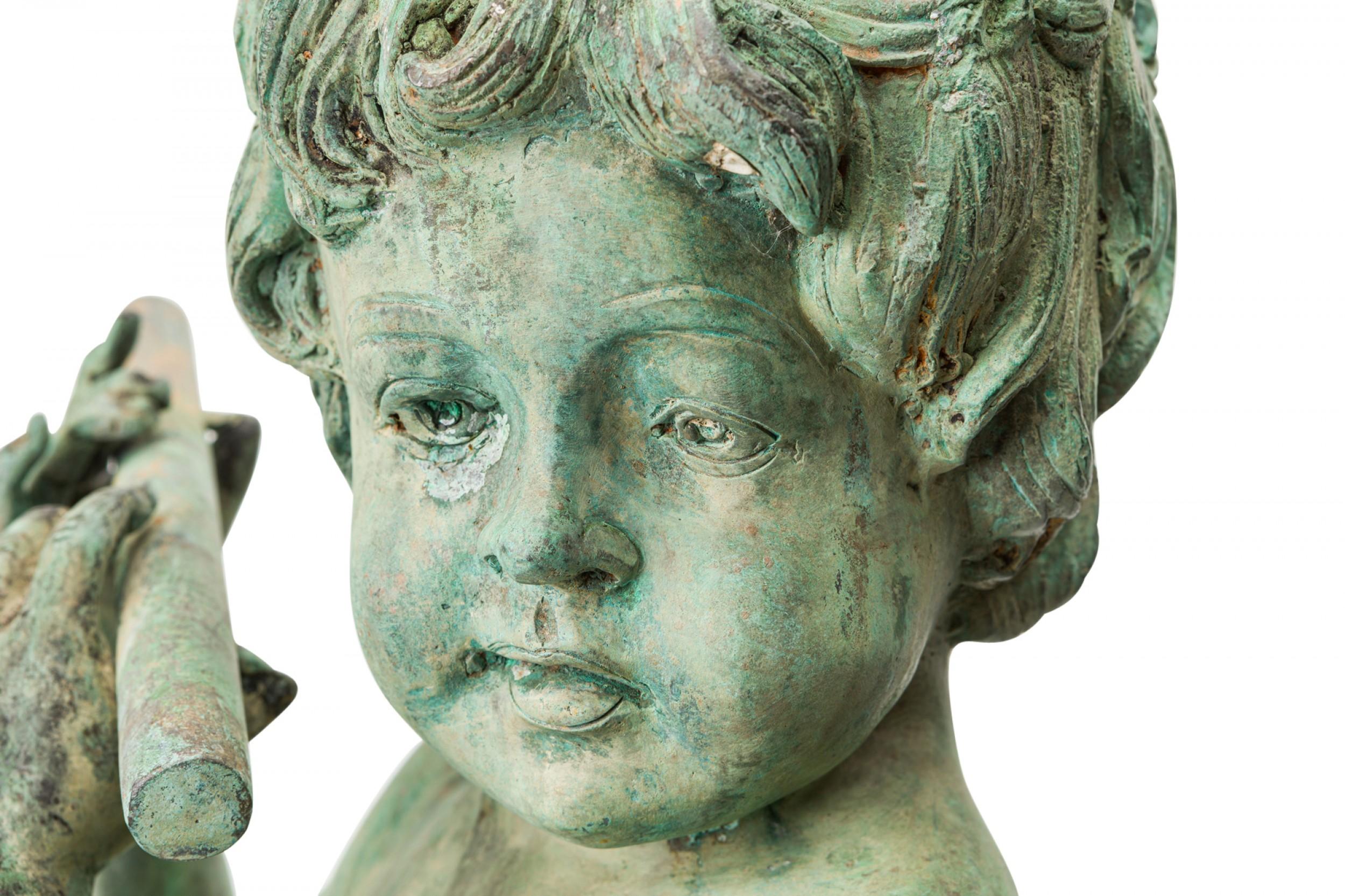 PAR de estatuas neoclásicas de hierro para exteriores de dos figuras de putti de tamaño natural, una con una pandereta y la otra con una mano de flauta, con pátina natural verde y marrón, que descansan sobre bases circulares de hierro. (PRECIO POR