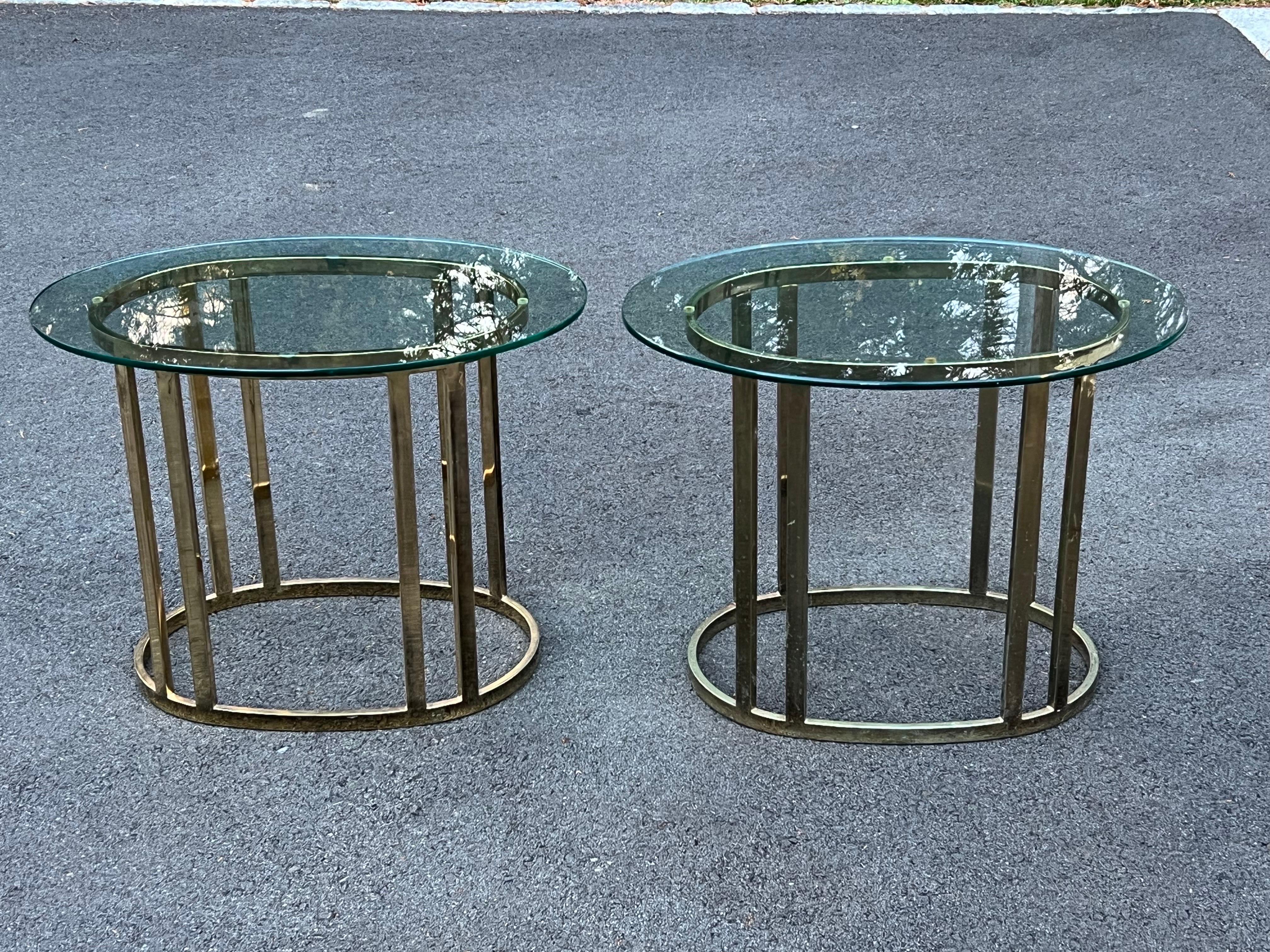 Pair of oval brass and glass end tables. Double banded vertical legs with oval base and base. Minimal lines and design. Price is for the pair of 2 total.