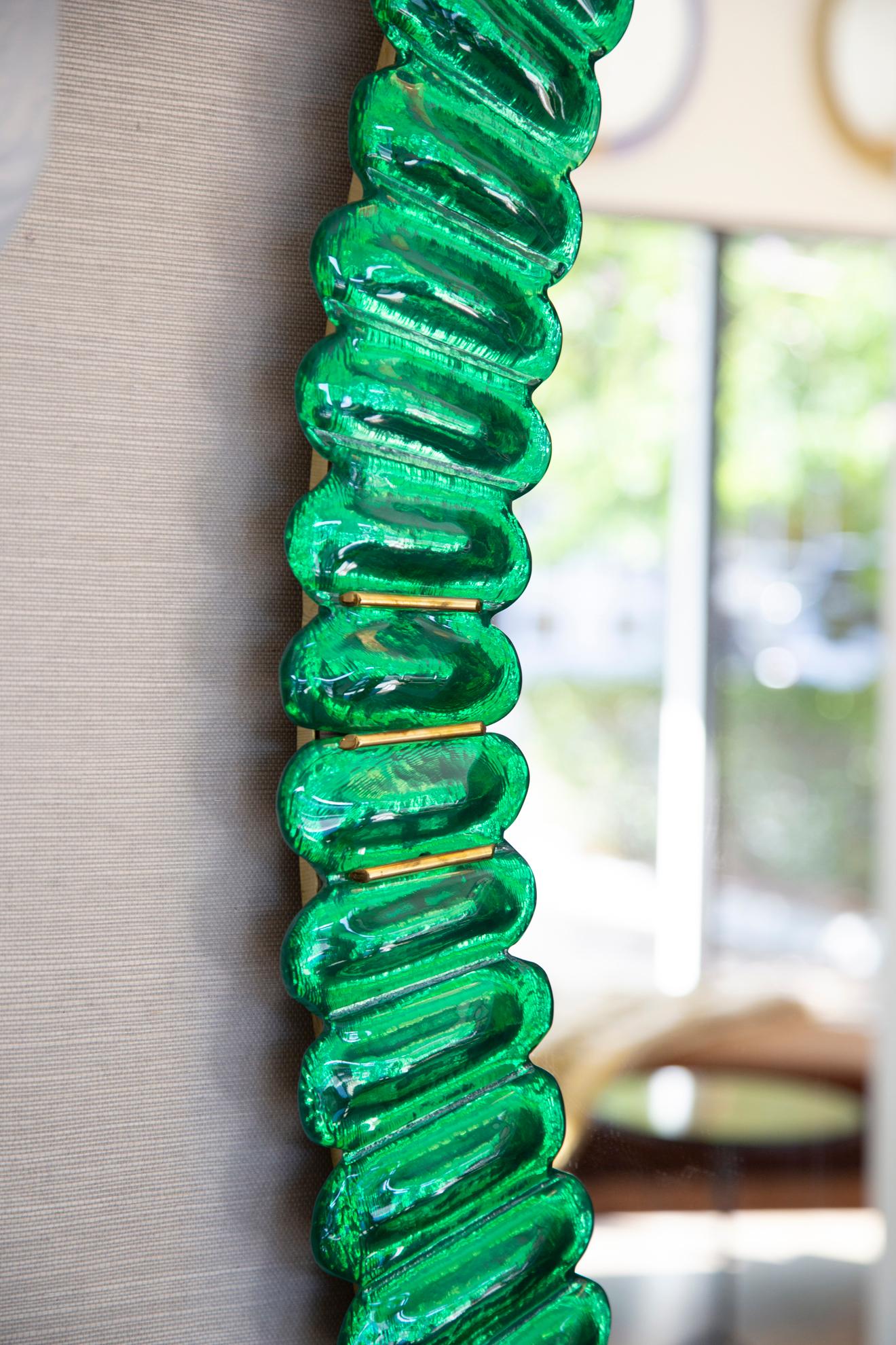 Oval emerald green Murano glass mirror, in stock now
Contemporary oval mirror with a scalloped Murano glass frame 
Brass accents
Handcrafted by a team of artisans in Italy
Can be easily hung vertically or horizontally with metal bracket on