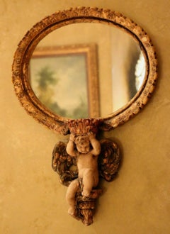 Pair of Oval Mirrors Polychromed and Held by Winged Cherub