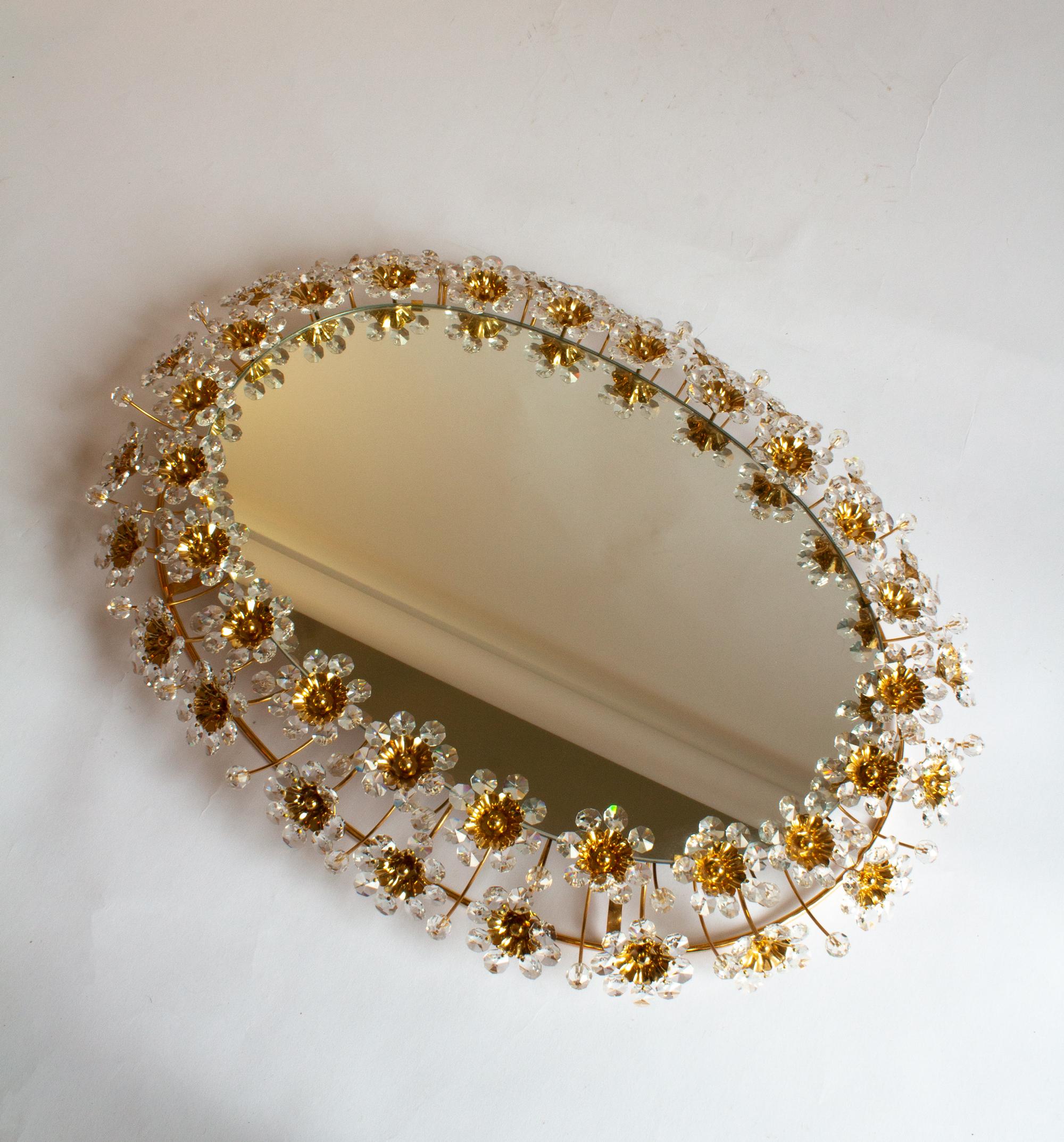Pair of oval Palwa backlight mirrors with guilt brass and crystal flowers.
These vintage flower mirrors was manufactured by Palwa in Germany. The mirrors is held by an oval guilt brass frame and a border of delicate little flowers made of faceted