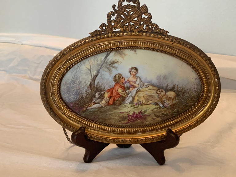 Charming pair of oval porcelain plaques with the frame in ormolu bronze represent scenes of a couple having fun in a landscape and the other one a couple having a nap with his kinght in a landscape.