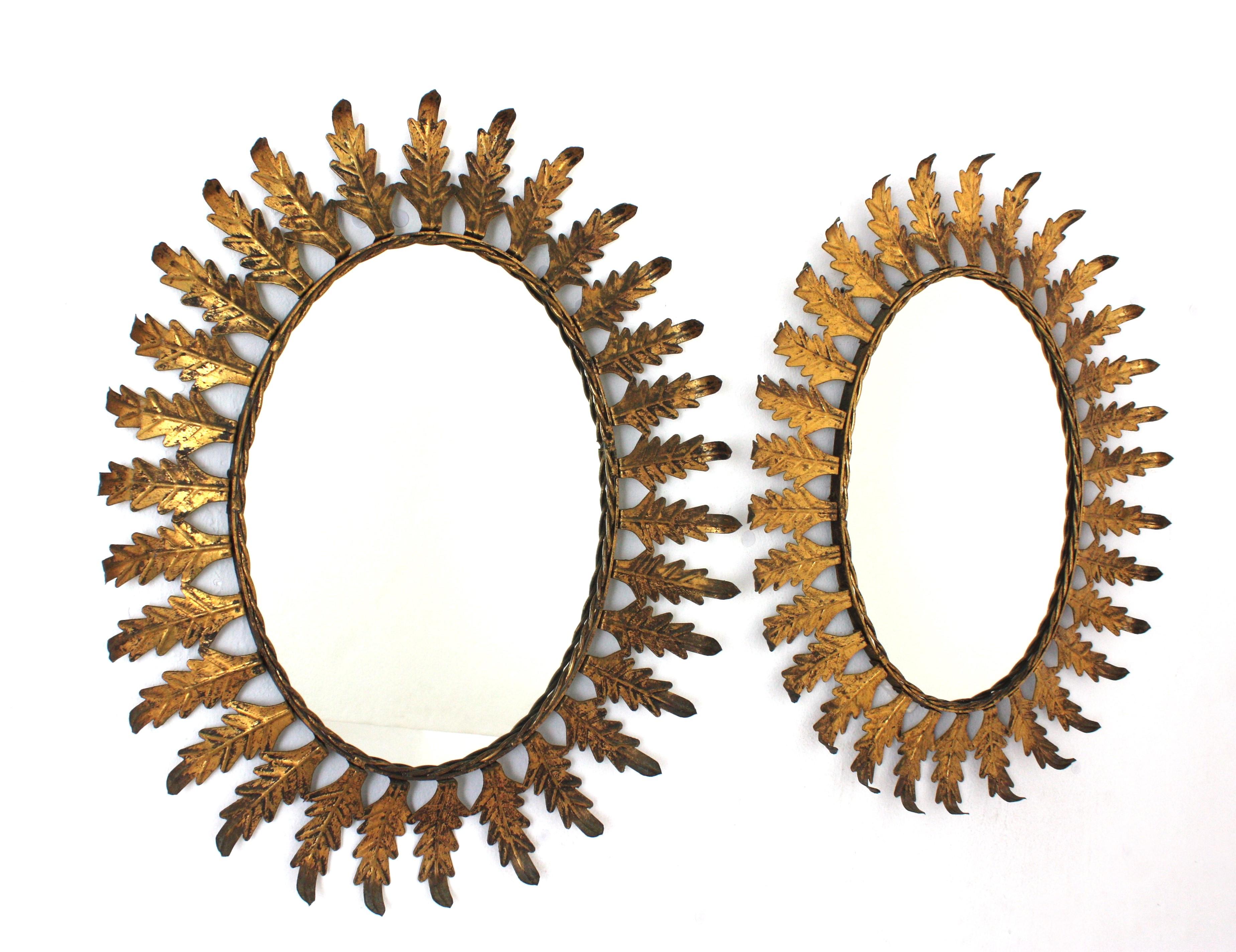 Pareja de Espejos Ovalados Sunburst en Hierro Dorado con Marco de Hojas, España Años 50 Moderno de mediados de siglo en venta