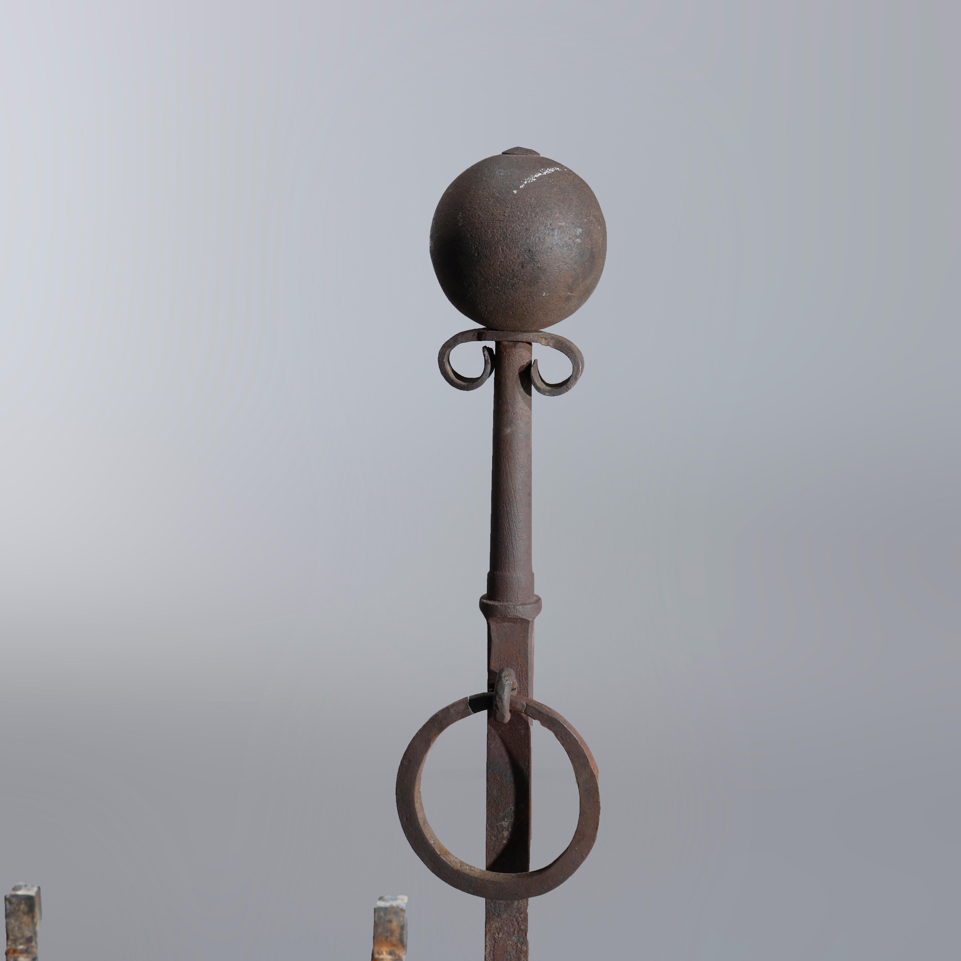 An antique pair of oversized andirons offers wrought iron construction with spherical ball finial surmounting shaft with ring, raised on cabriole legs, 19th century.

Measures: 32.5