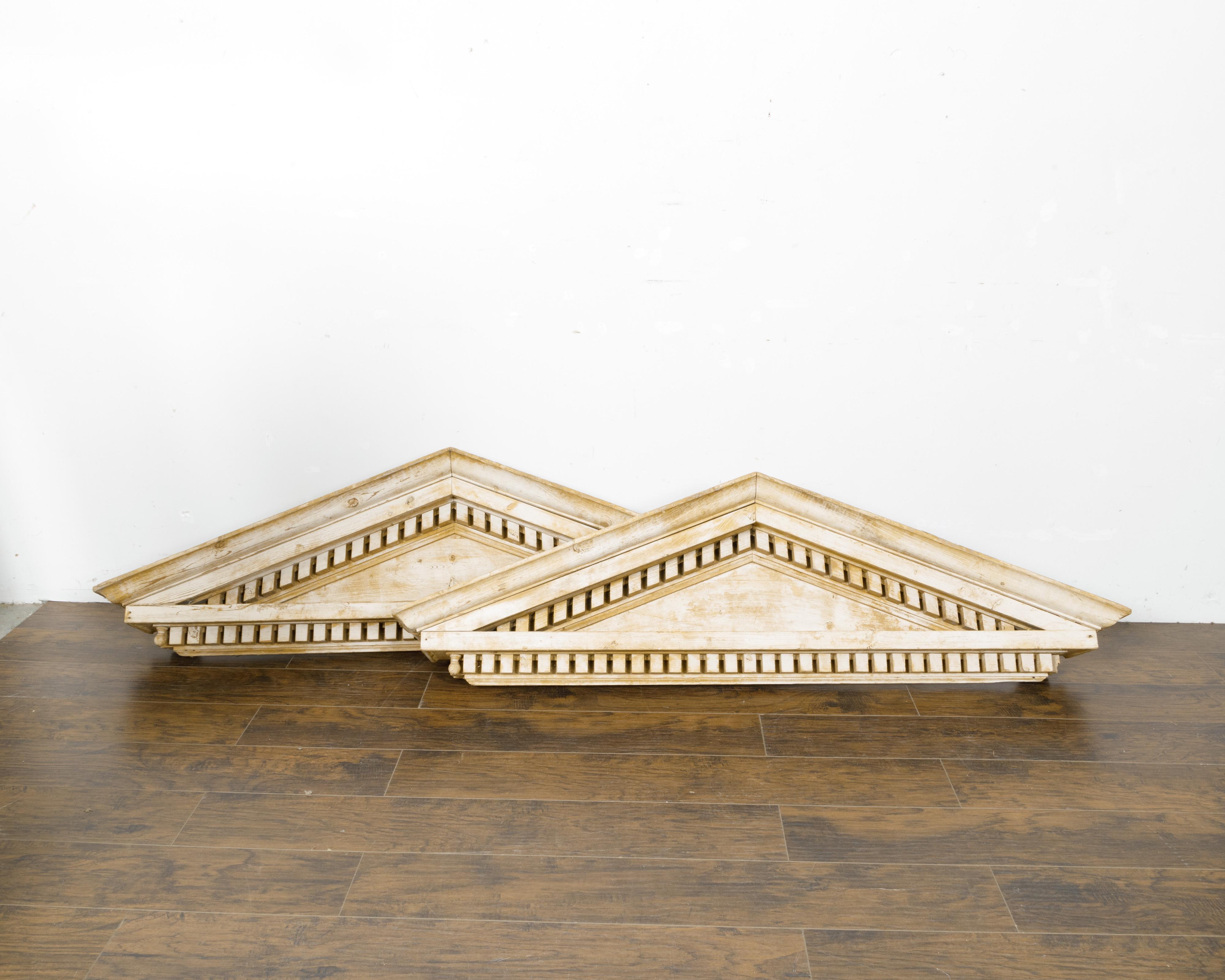 A pair of oversized English pine triangular pediments from the 19th century with carved dentil molding. This pair of oversized English pine triangular pediments from the 19th century is a testament to the timeless elegance of classic architectural