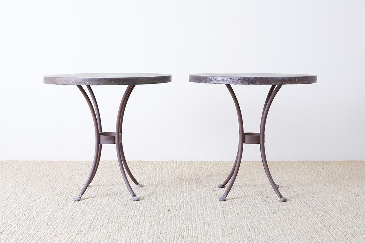 Pair of French bistro style round copper top dining tables featuring a hand-hammered finish. Constructed by California artisans O.W. Lee with a galvanized steel base and a beautifully patinated copper metal finish with verdigris. Part of a large