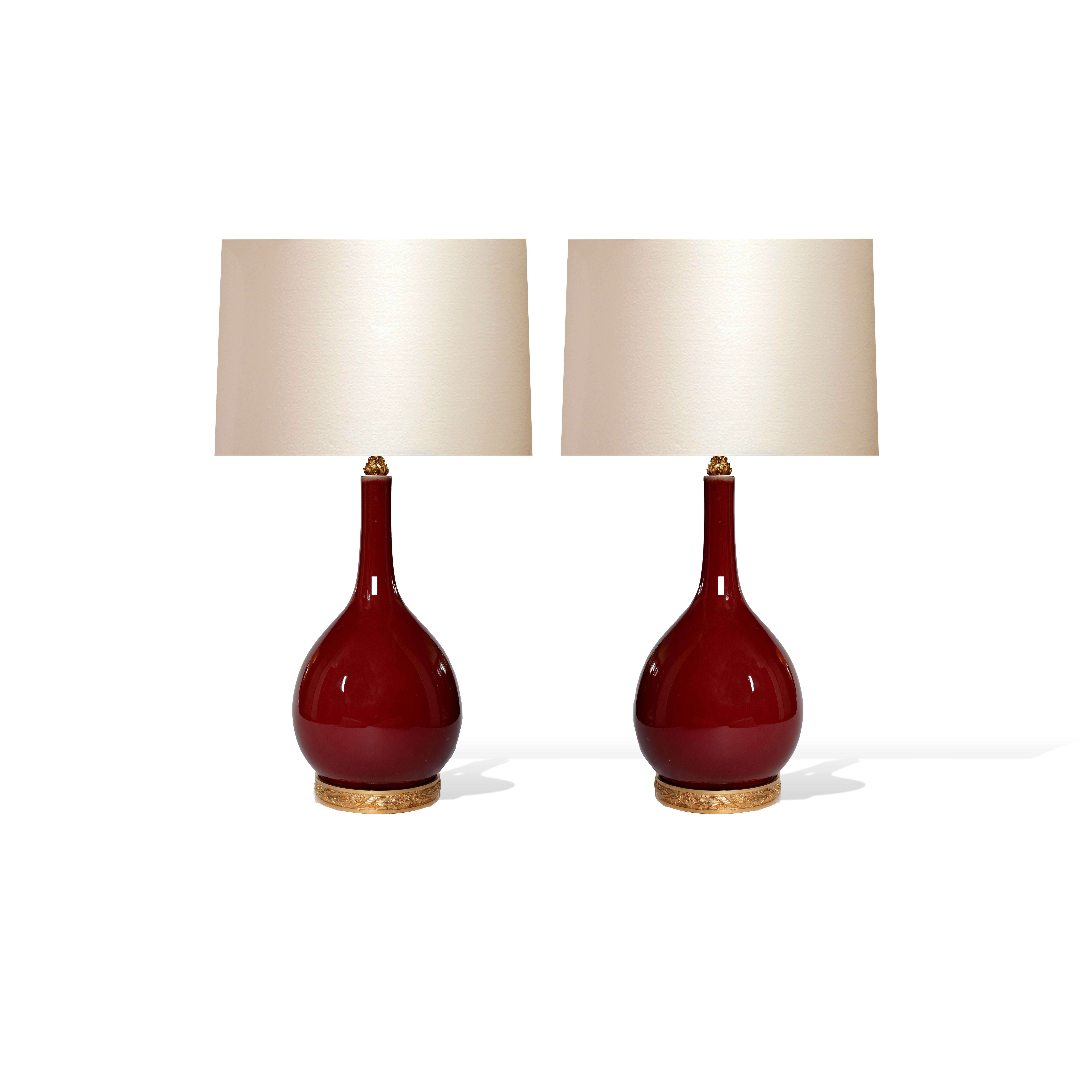 Pair of oxblood glazed porcelain lamps with gilt brass bases,
Each lamp installed two sockets, e26 bases, to the top of the porcelain 21 inch.