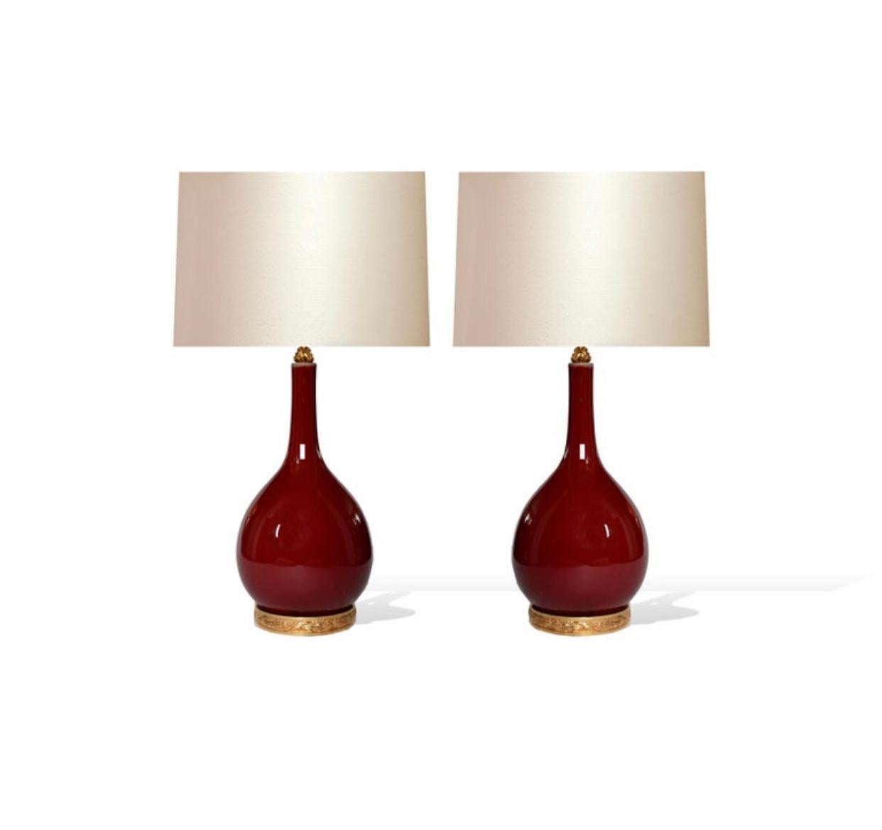 Pair of oxblood glazed porcelain lamps with gilt brass bases,
Each lamp installed two sockets, e26 bases, to the top of the porcelain 21 inch.