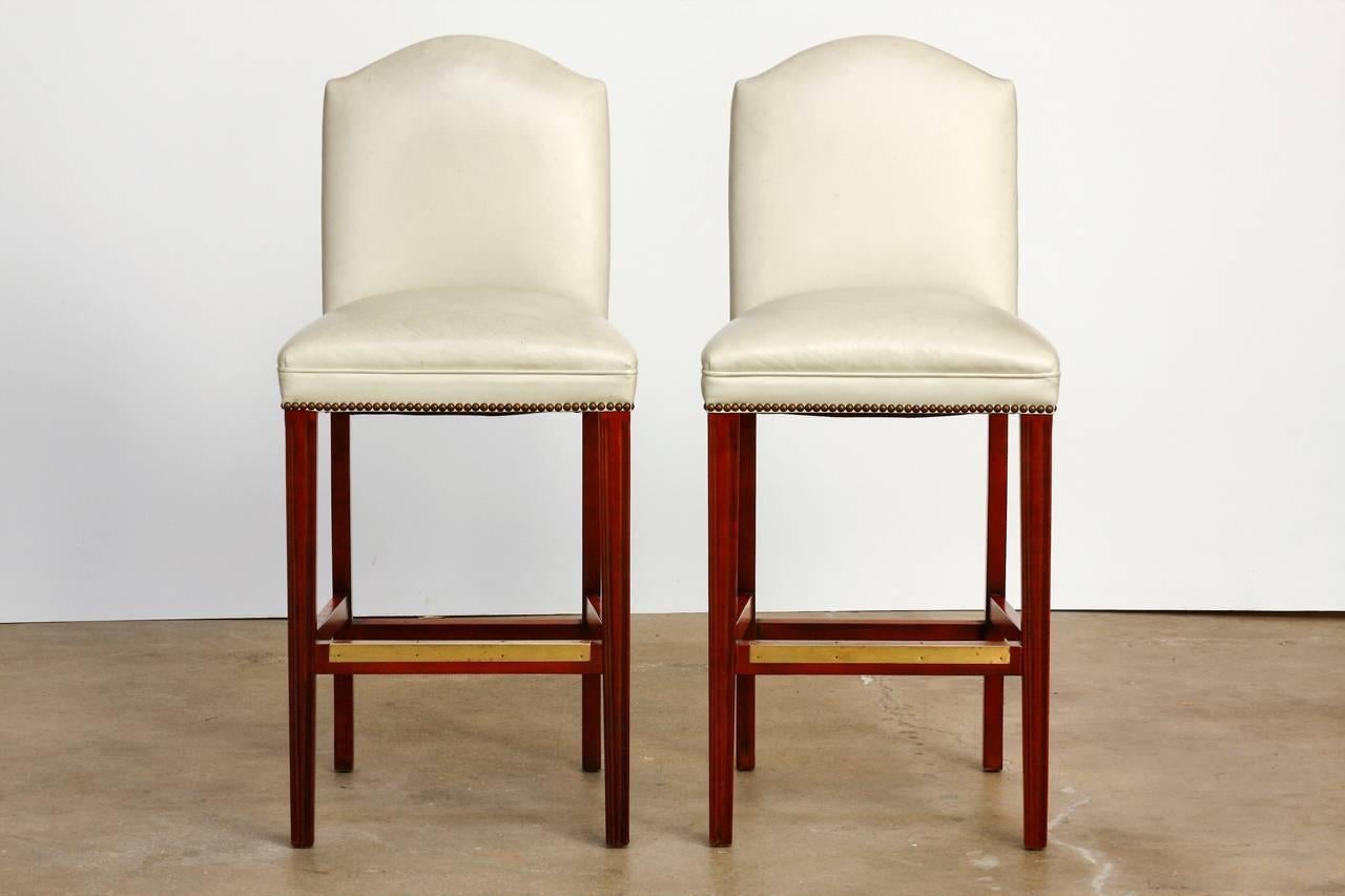 Handsome pair of oyster color leather high backed bar stools or counter stools made in Hickory, North Carolina. Featuring a beautiful leather upholstery accented by brass nailheads. Designed with a deep seat and a humpback support. Supported by