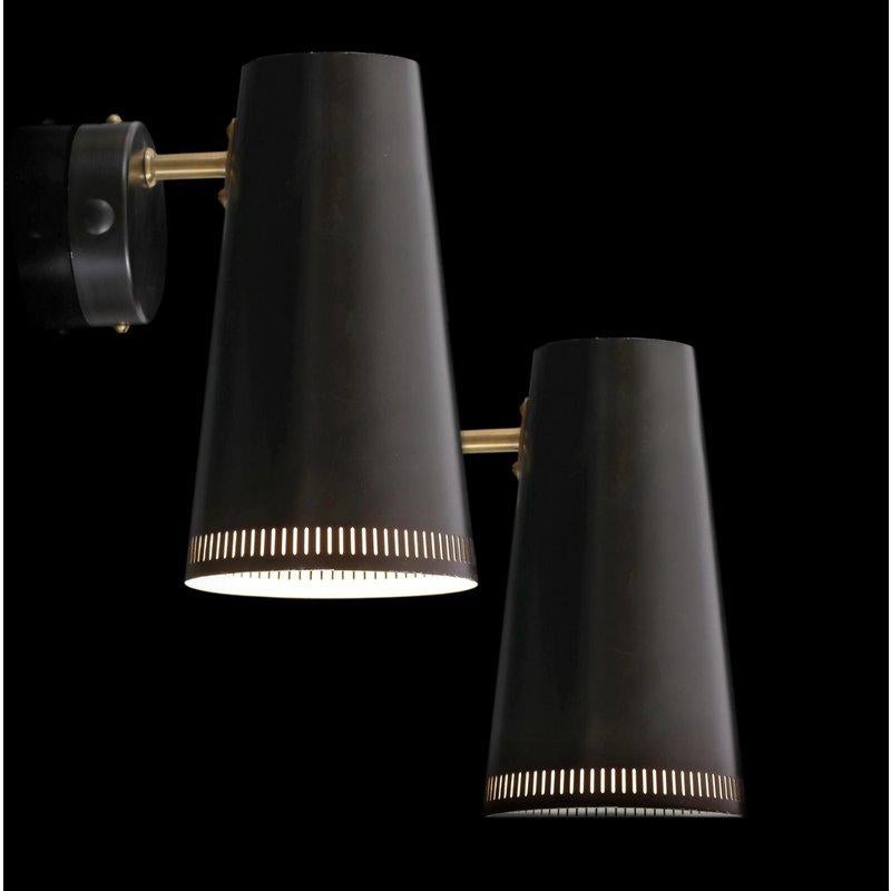 A distinctive pair of wall lights by Paavo Tynell for Taito Oy with black lacquered metal shades and brass stems. Completely original and in excellent shape. Marked 