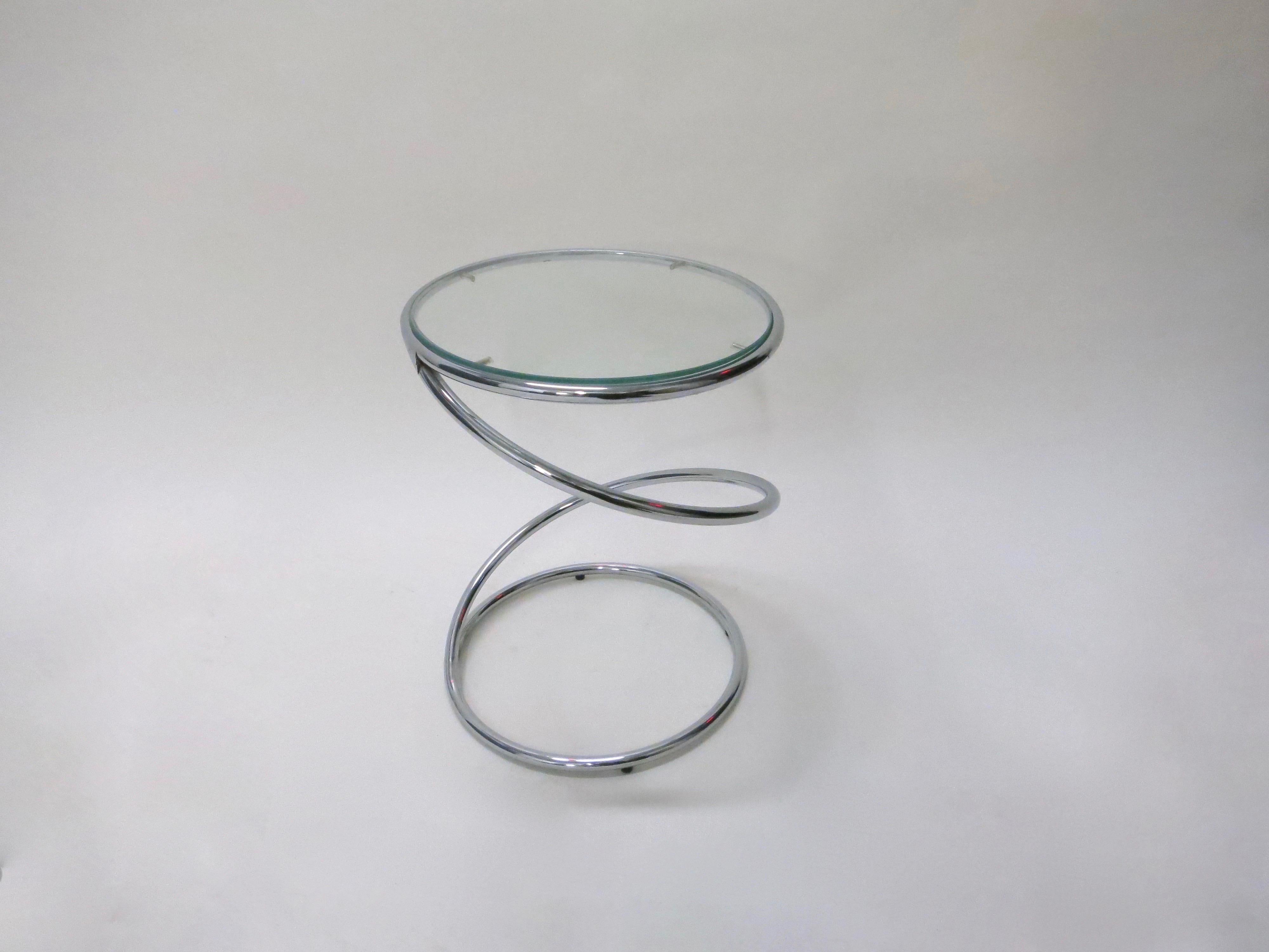 Pair of chromed metal tables in the shape of a spiral each with a round clear glass top supported on a round base with four feet on the bottom. Black mirrored glass tops also available, as shown in the last image.