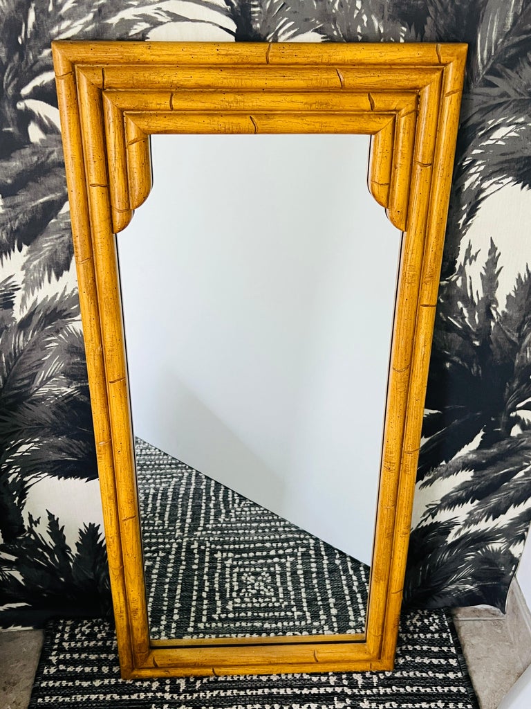 Pair of Hollywood Regency style faux bamboo mirrors with carved wood and resin frames.
The chic mirrors have an Asian pagoda inspired design with narrow frames.  Featuring hand-carved bamboo motif and antique stained finish.  