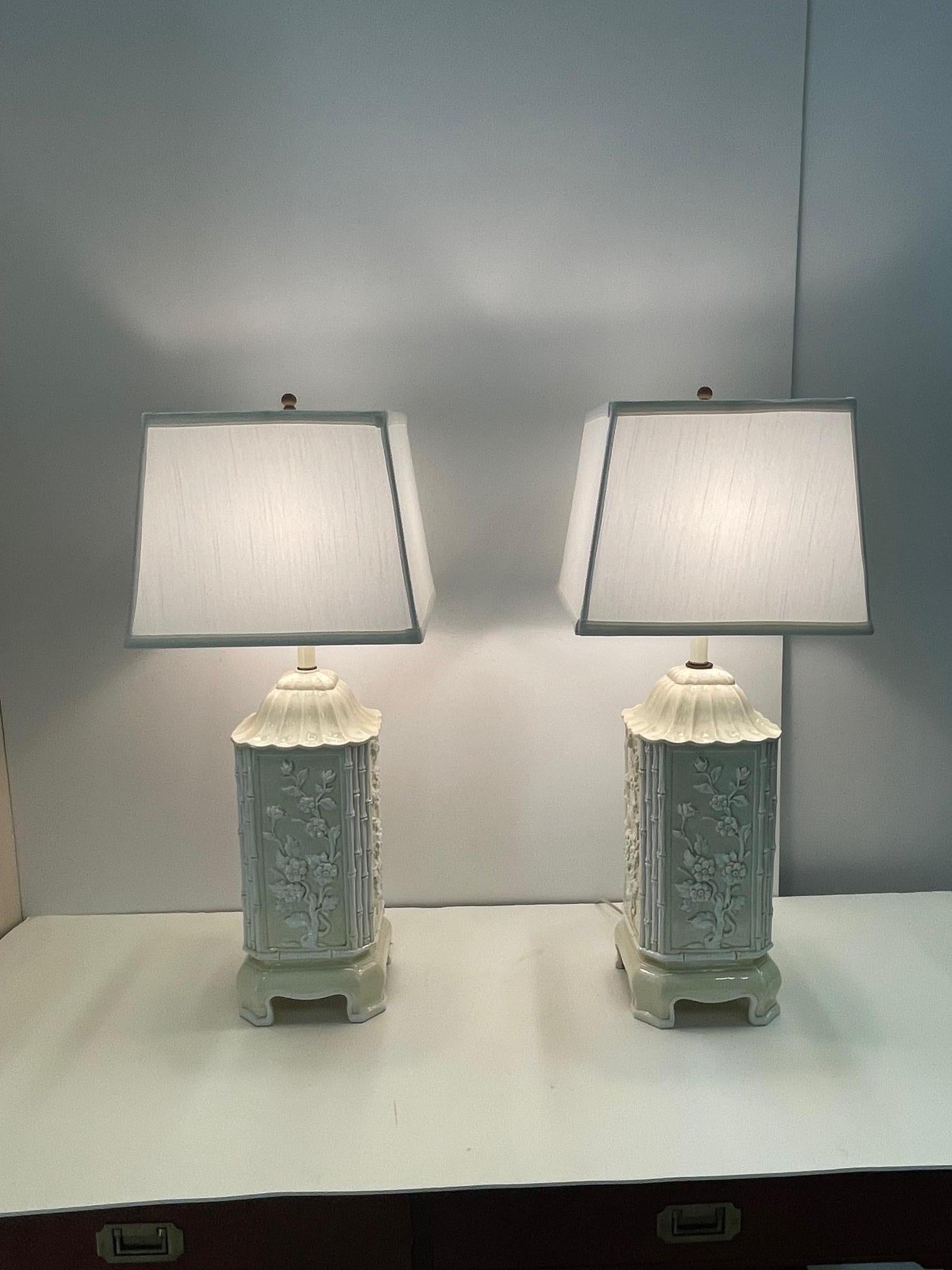 Lovely pair of Italian ceramic table lamps having khaki very light yellow beige background and white raised bamboo and floral decoration. The lamps have an Asian flair with pagoda design and raised stands.