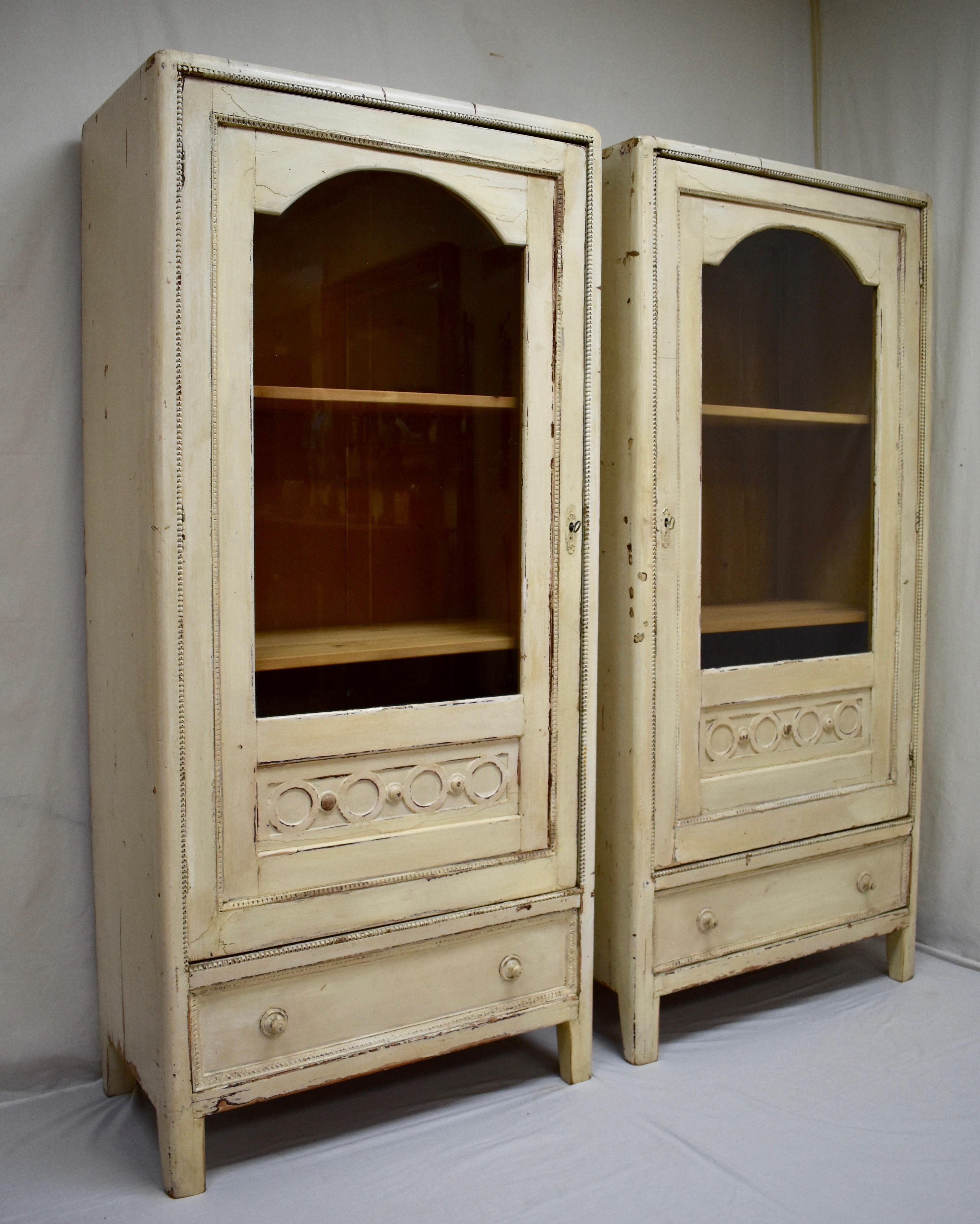This is a matched pair of truly “shabby chic” glazed cabinets or vitrines with smooth and elegant decorative features. The crown has no molding but is rounded over, exposing hand-cut dovetails where the paint has worn away. The sides extend to the